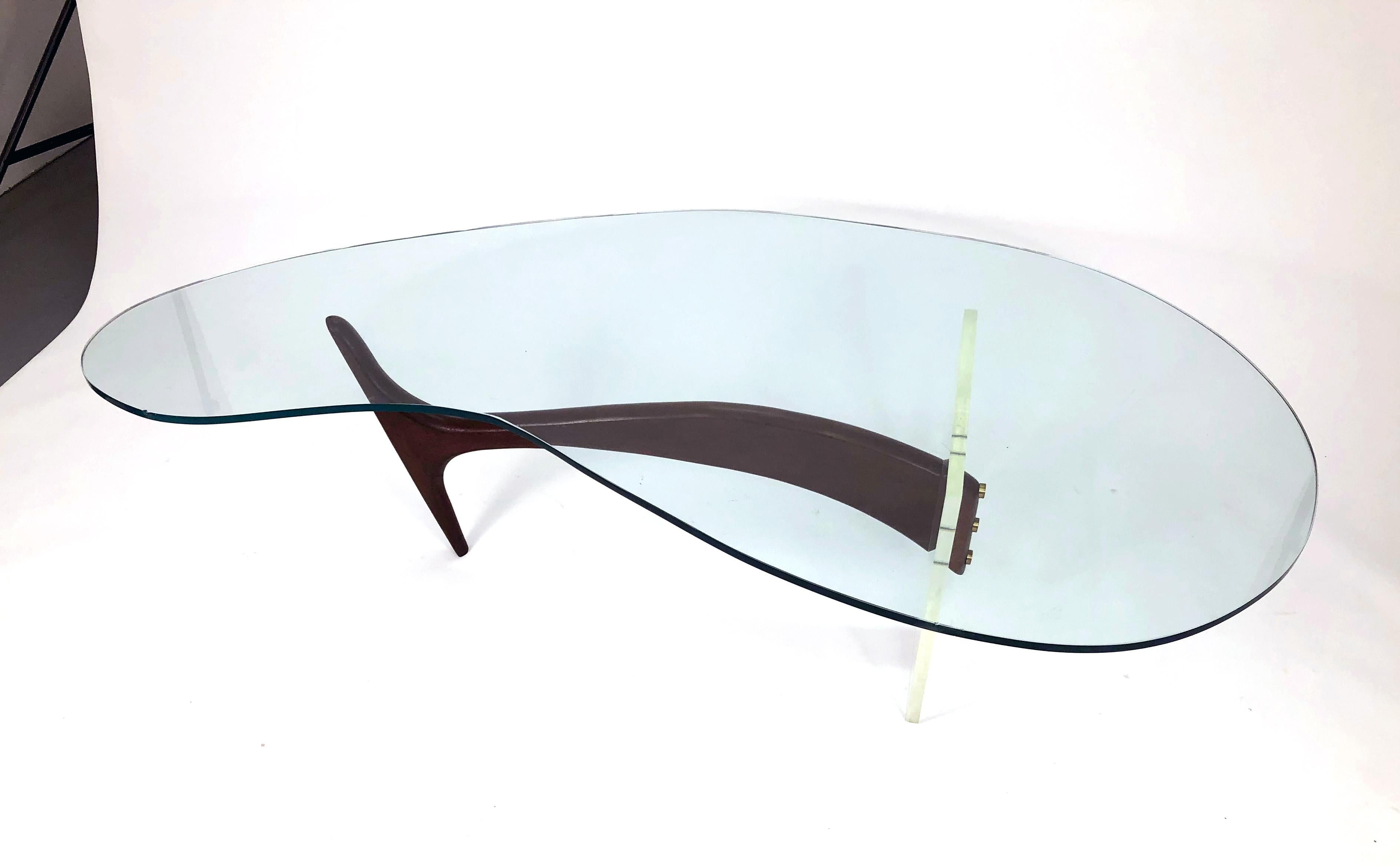 Stunning vintage coffee table with asymmetrical 'boomerang' glass top supported by a sculpted walnut, brass, and Lucite base attributed to Vladimir Kagan. 

Brass accent caps conceal the threaded screws that hold the Lucite panel between the two