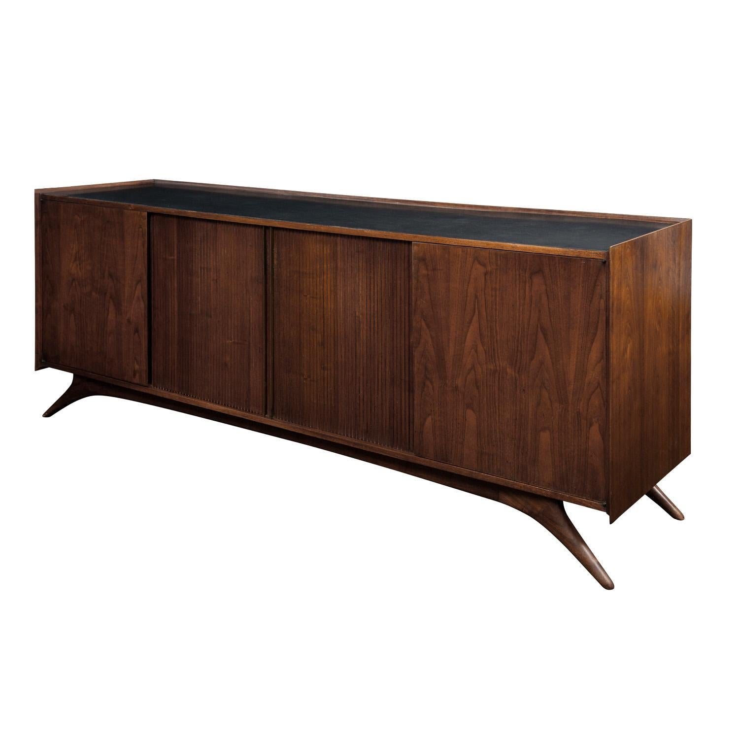 Credenza in walnut with signature splayed legs, tambour doors and black laminate top by Vladimir Kagan for Grosfeld House, American, 1950's. A beautiful Kagan design.

Reference:
The Complete Kagan published by Pointed Leaf Press LLC in 2004, pages