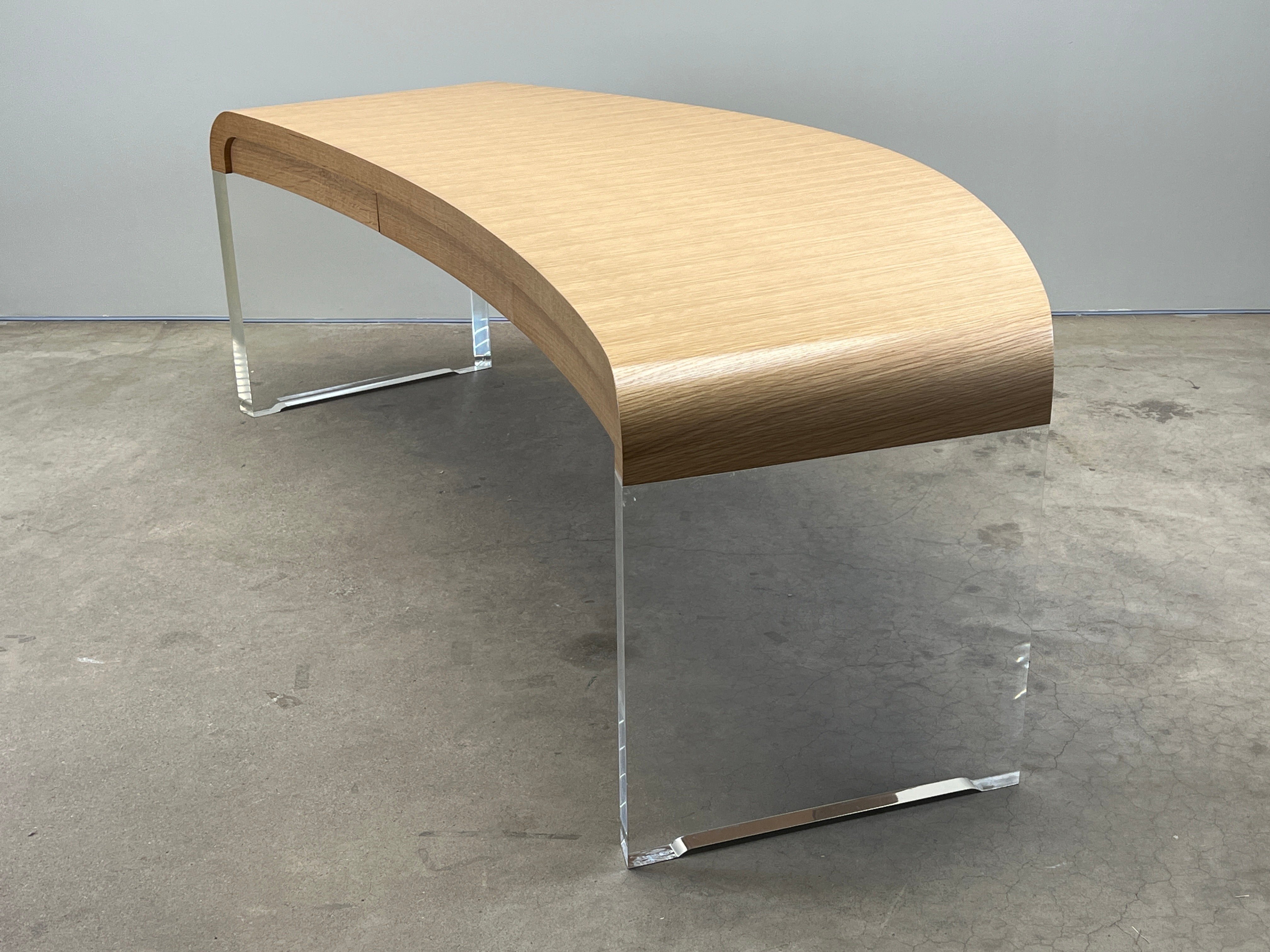 Una scrivania elegantemente curvata con spesse gambe in lucite e piano in quercia bianca. Progettato da Vladimir Kagan. 