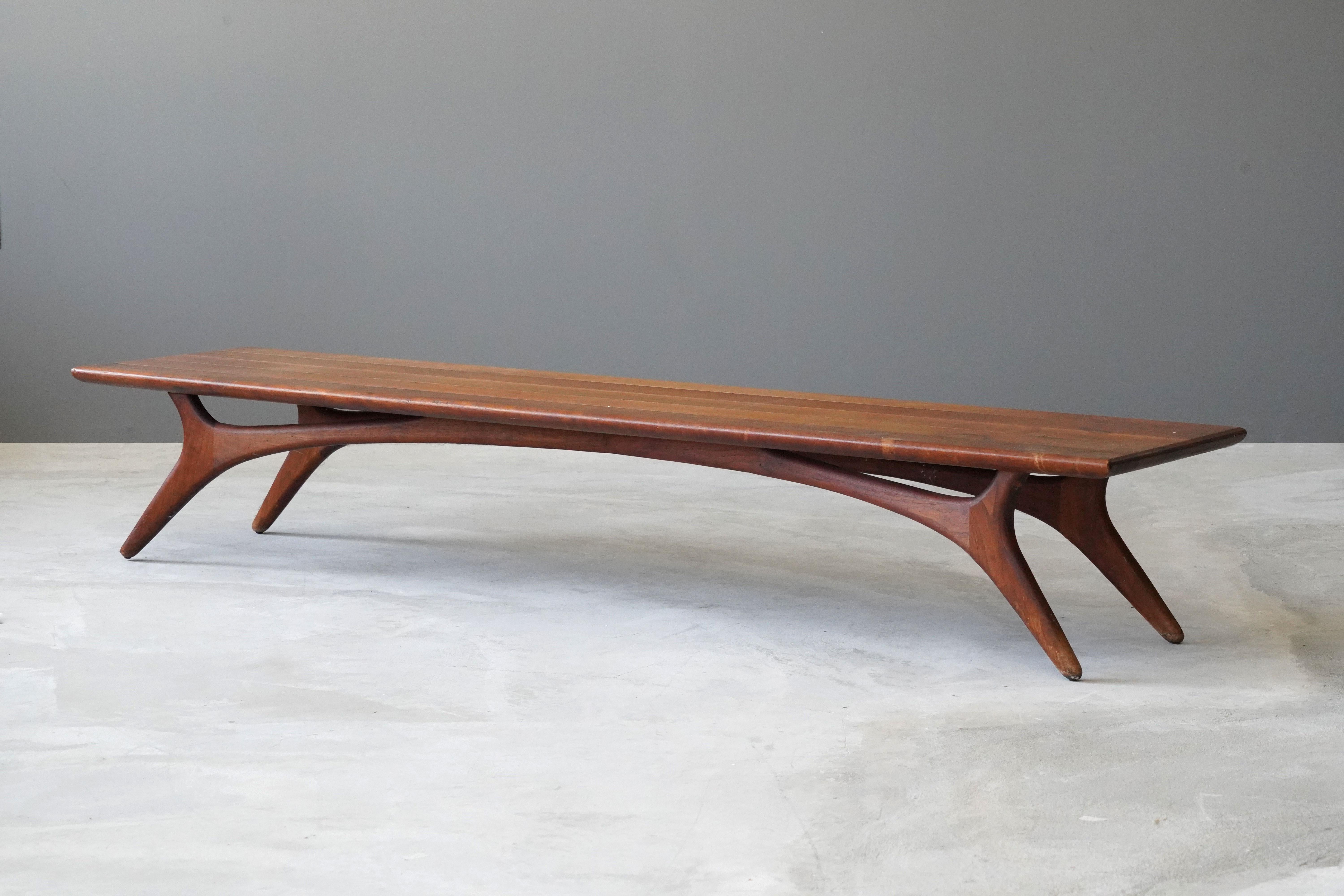 A rare long bench or cocktail / coffee table. Designed by Vladimir Kagan and produced by Grosfeld House, 1950s. In finely sculpted walnut, typical to Kagan. 

