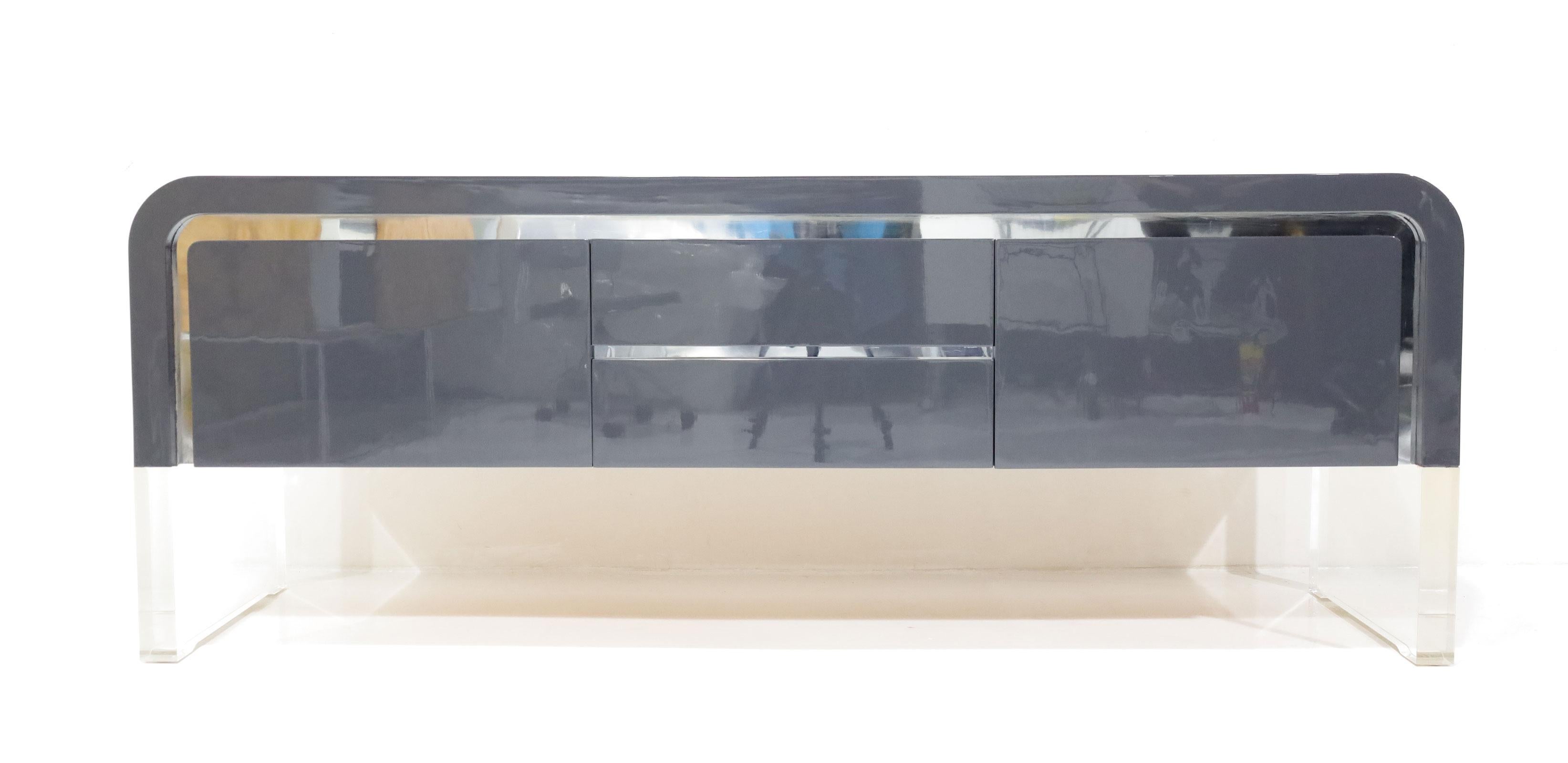 Il bordo liscio a cascata della Ribbon Credenza è la risposta di Kagan alla cassa rettilinea. Scendendo a cascata in un'unica linea continua o evaporando nelle gambe in lucite, questo design del 1979 incarna la funzionalità dell'archiviazione con un