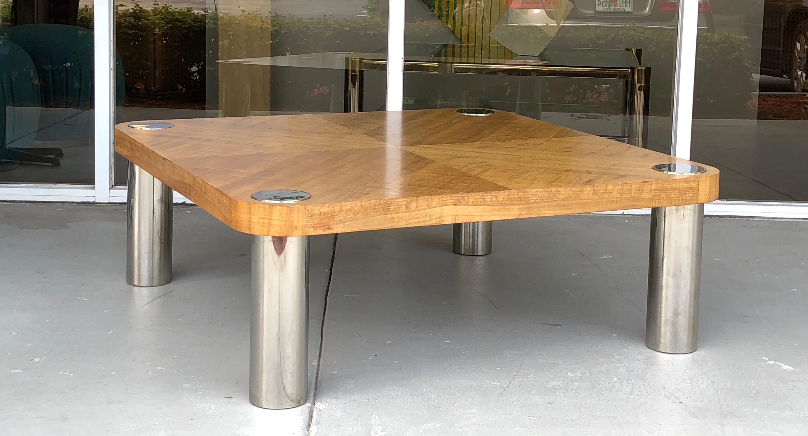 A Vladimir Kagan designed coffee table. The wood on top creates a subtle modern pattern. Large polished stainless legs. Signed on verso of top with label.