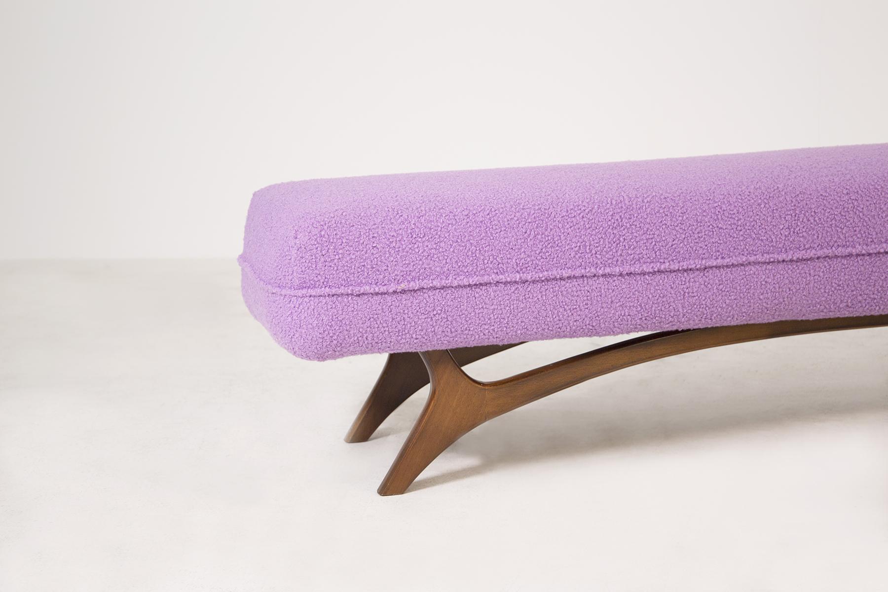 American vintage bench from the. The bench has been restored and reupholstered in an elegant lilac bouclé fabric. The bench has a wooden frame with special attention to its semi-curved feet that align with the frame.
The special feature of the