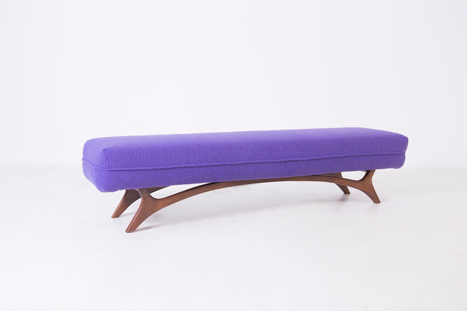 American bench from the 1950s. The bench has been restored and reupholstered in an elegant purple bouclé fabric. The bench has a wooden frame with special attention to its semi-curved feet that align with the frame.
The special feature of the bench