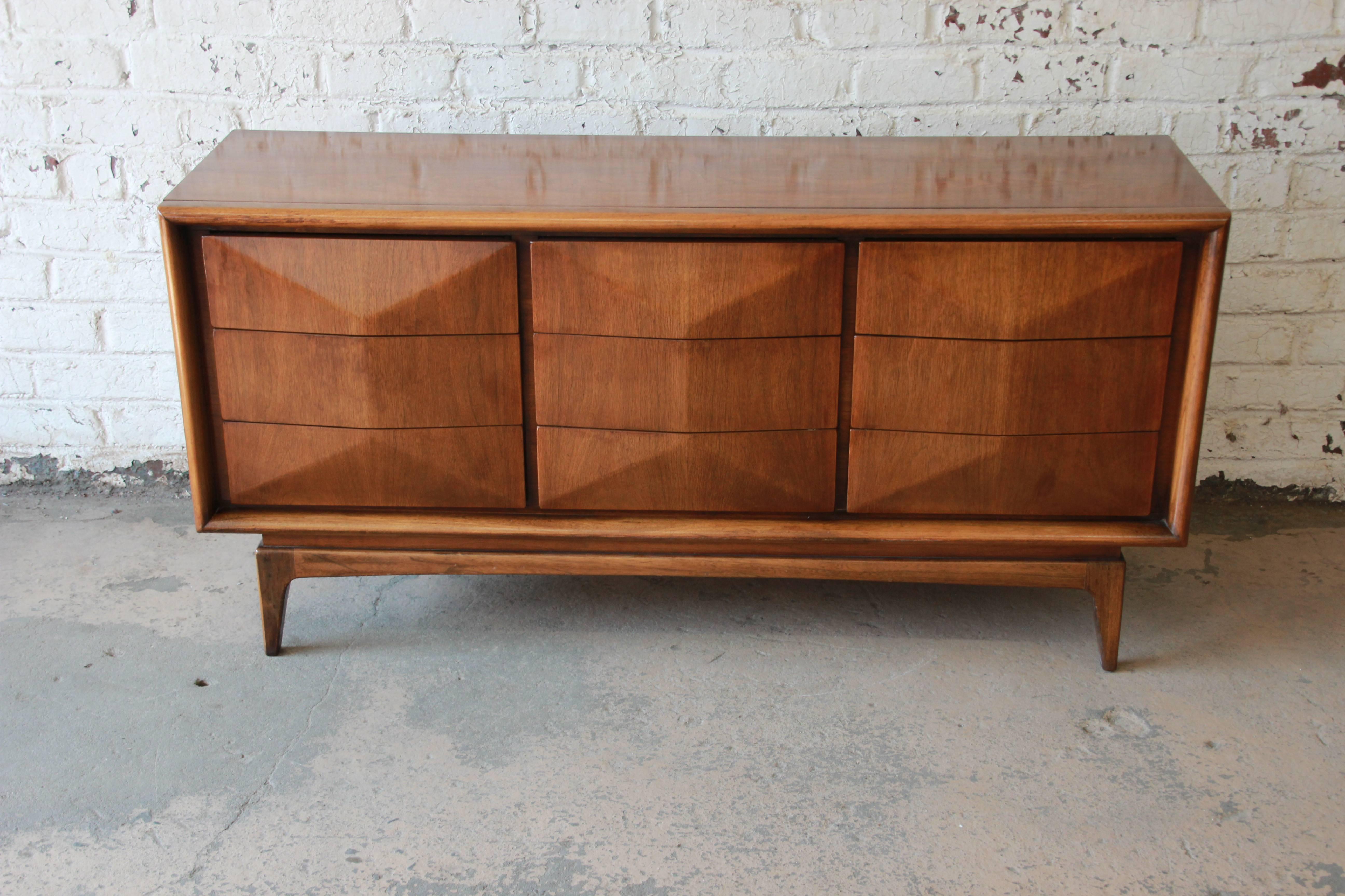An exceptional and unique Mid-Century Modern diamond front dresser or credenza by United Furniture in the style of Vladimir Kagan. The dresser features stunning walnut wood grain and a sculpted diamond front with nine hefty drawers. It is well