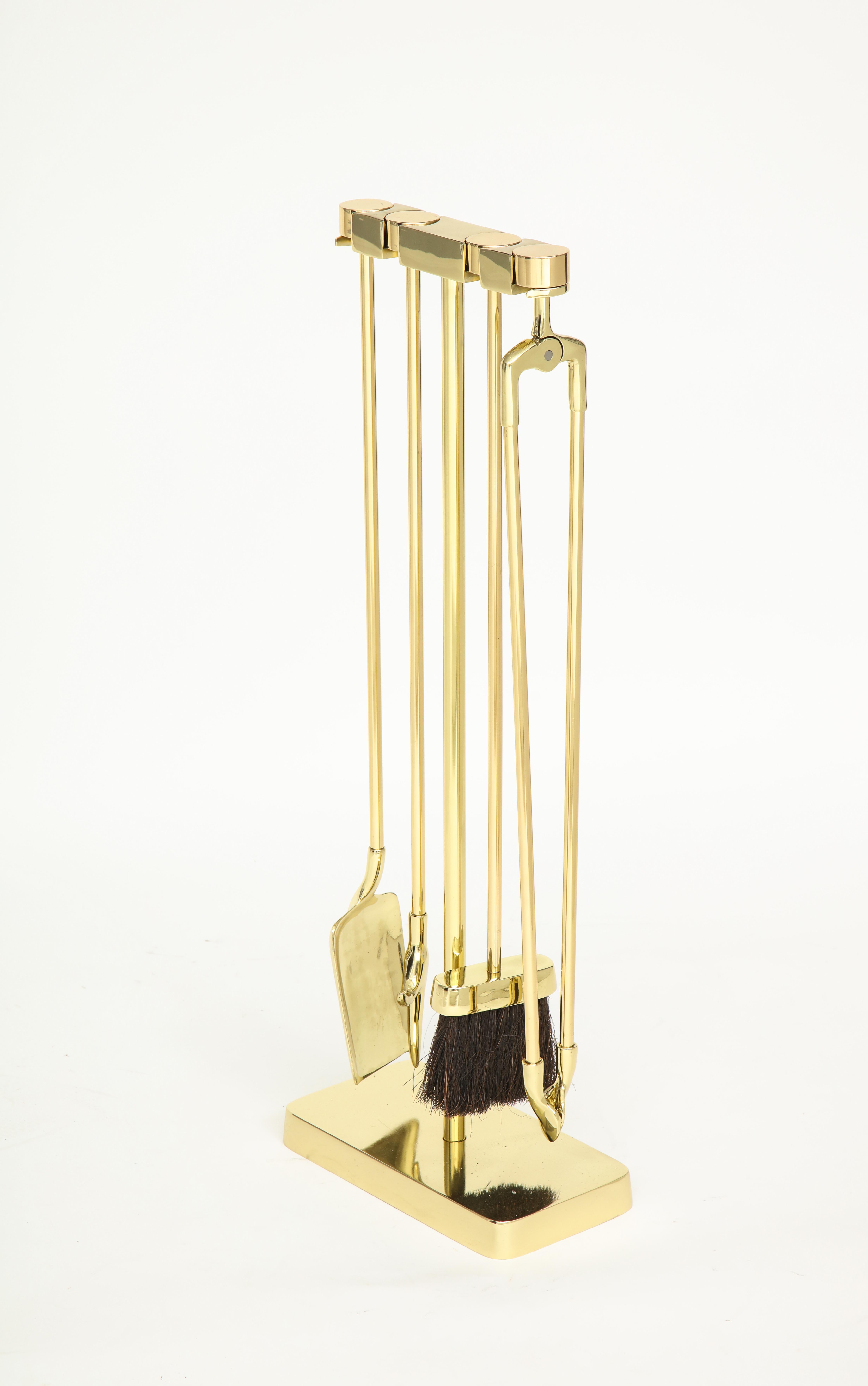 Set of heavy brass modernist firetools suspended on a heavy brass stand. The Minimalist designed handles cleverly slide into the stand.