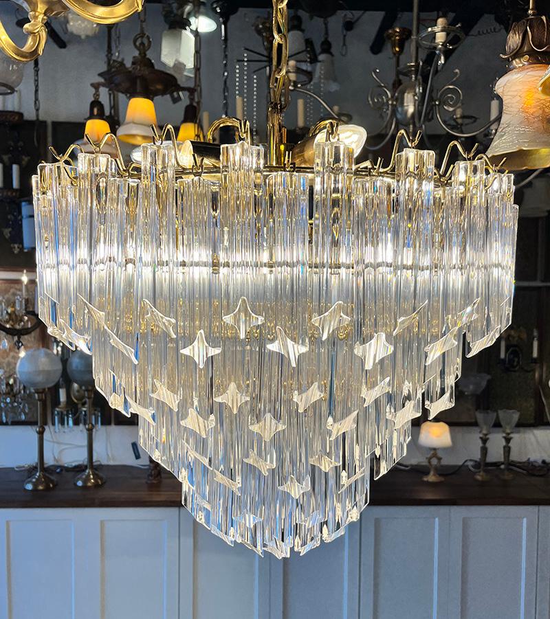 Beautiful original Venini four tiered chandelier with four sided glass quadrilobo prisms. Original gold toned polished brass frame and finish. Stunning addition to an entrance, living room or dining room. All prisms are removable for installation or