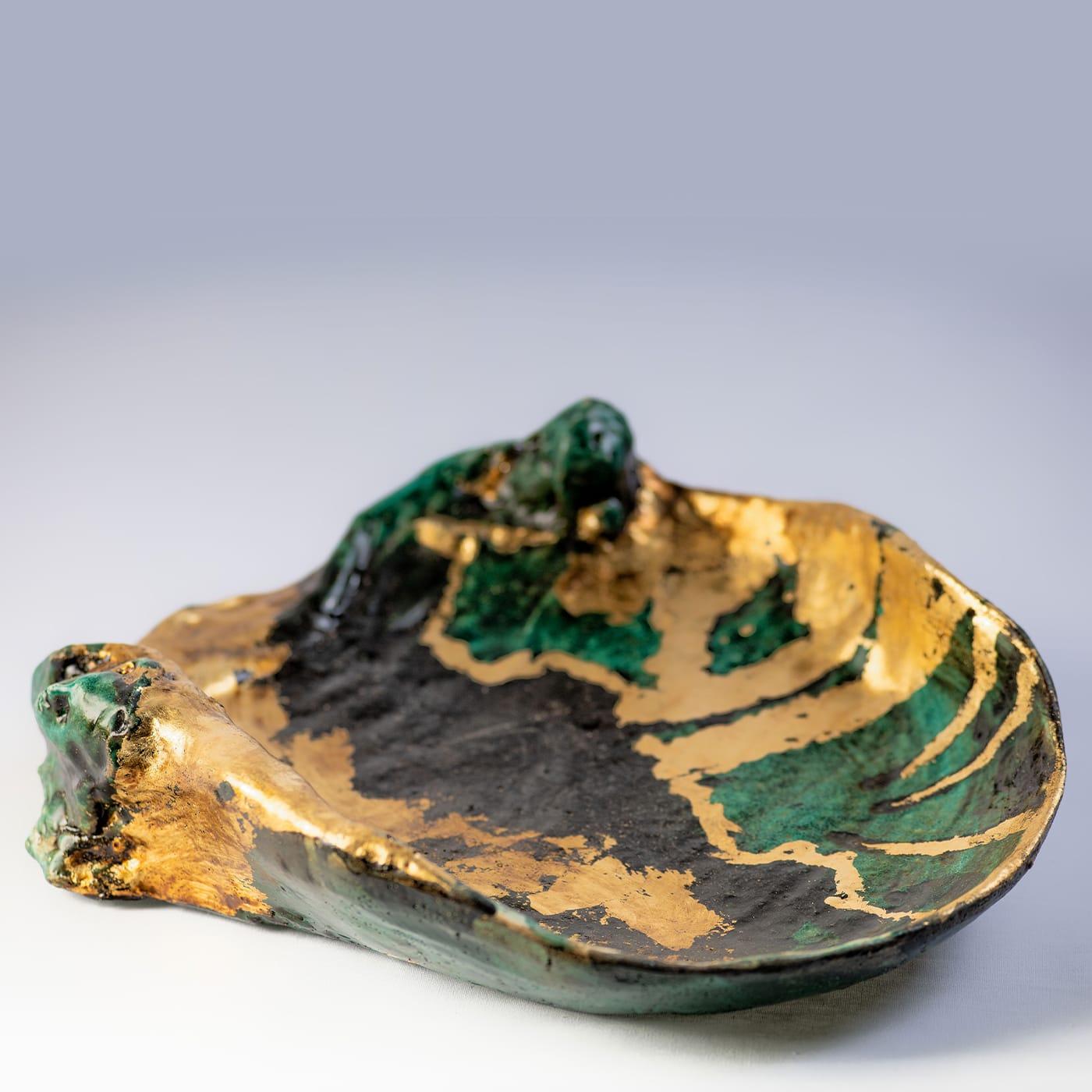 Playing with the interaction of verdigris and black glazes veined with lavish accents of gold leaf, artist Angelo Salemi handcrafted this sublime ceramic centerpiece bowl. Two human faces seem to emerge from the sides, giving this deliberately