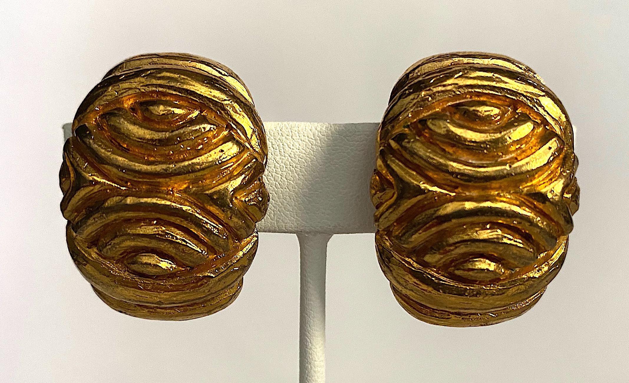 An elegant and sculptural pair of gold plate earrings by Italian fashion jewelry company Vogue Bijoux from the 1980s. The oval shape earrings are carefully cast with a carved abstract design. They are lightly domed and curved. Each measures .94 of