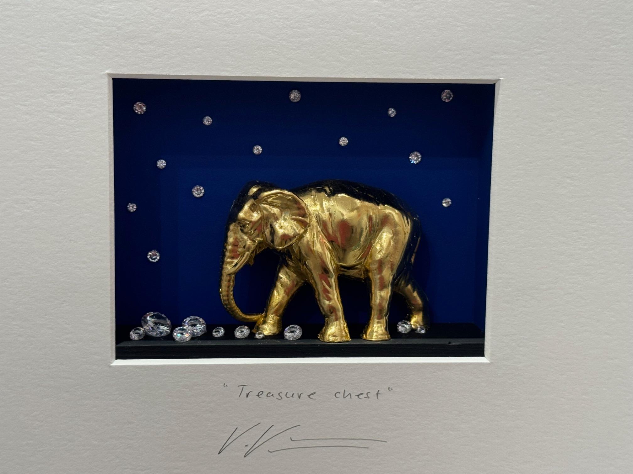 "Treasure Chest" is an original mixed media artwork by Volker Kuhn. A golden elephant hording gemstones. The work is hand-signed by the artist below the artwork on the mat. It is a funny minimalist work formed as a hand-made assemblage carved out