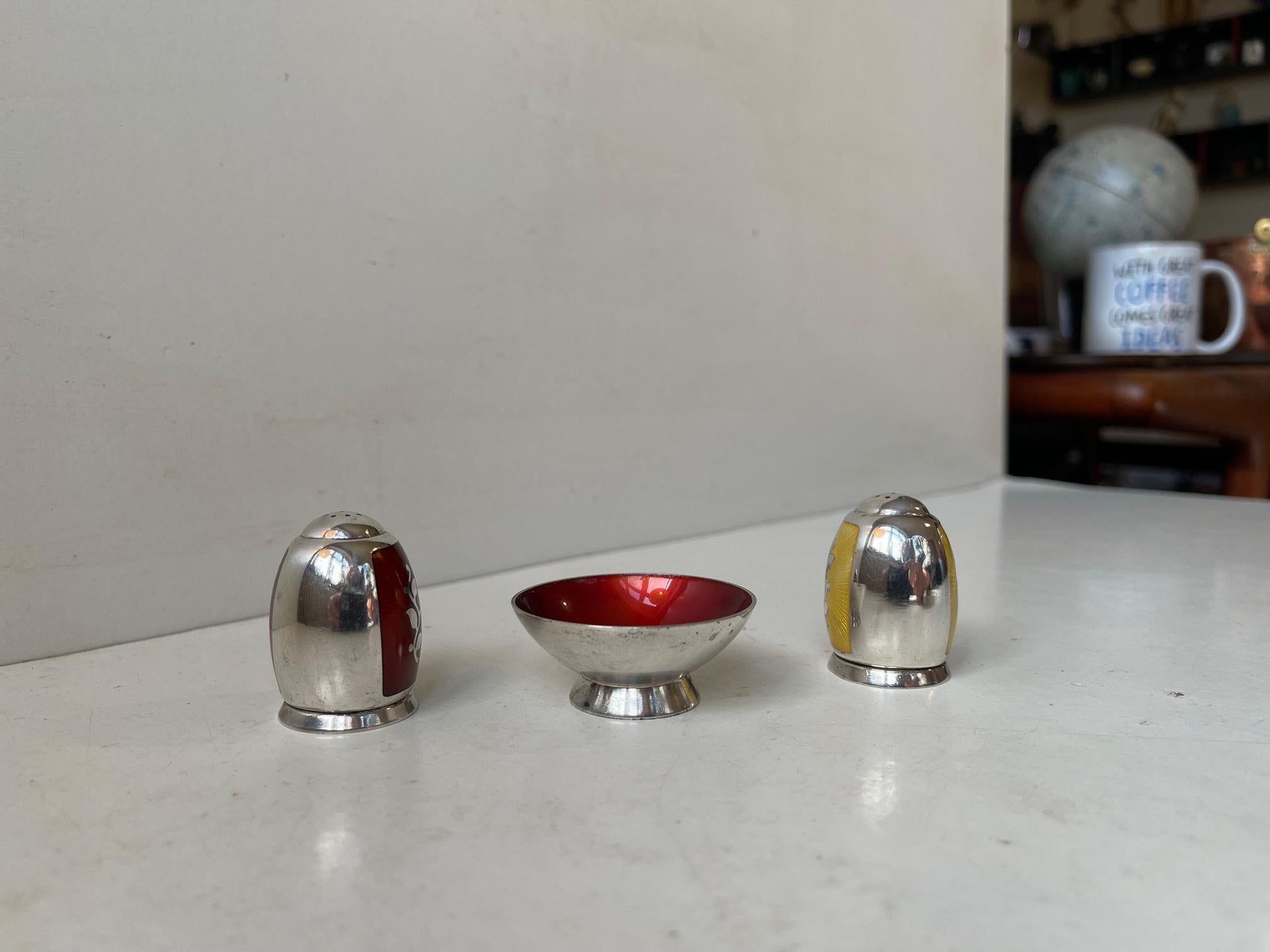 Beautiful set consisting of salt and pepper shaker in sterling silver and maroon/red and lemon yellow enamel guilloche. This set is accompanied by a small footed sterling and enamel jar for finger salt, spices, caviar or sugar. The 3 pieces are