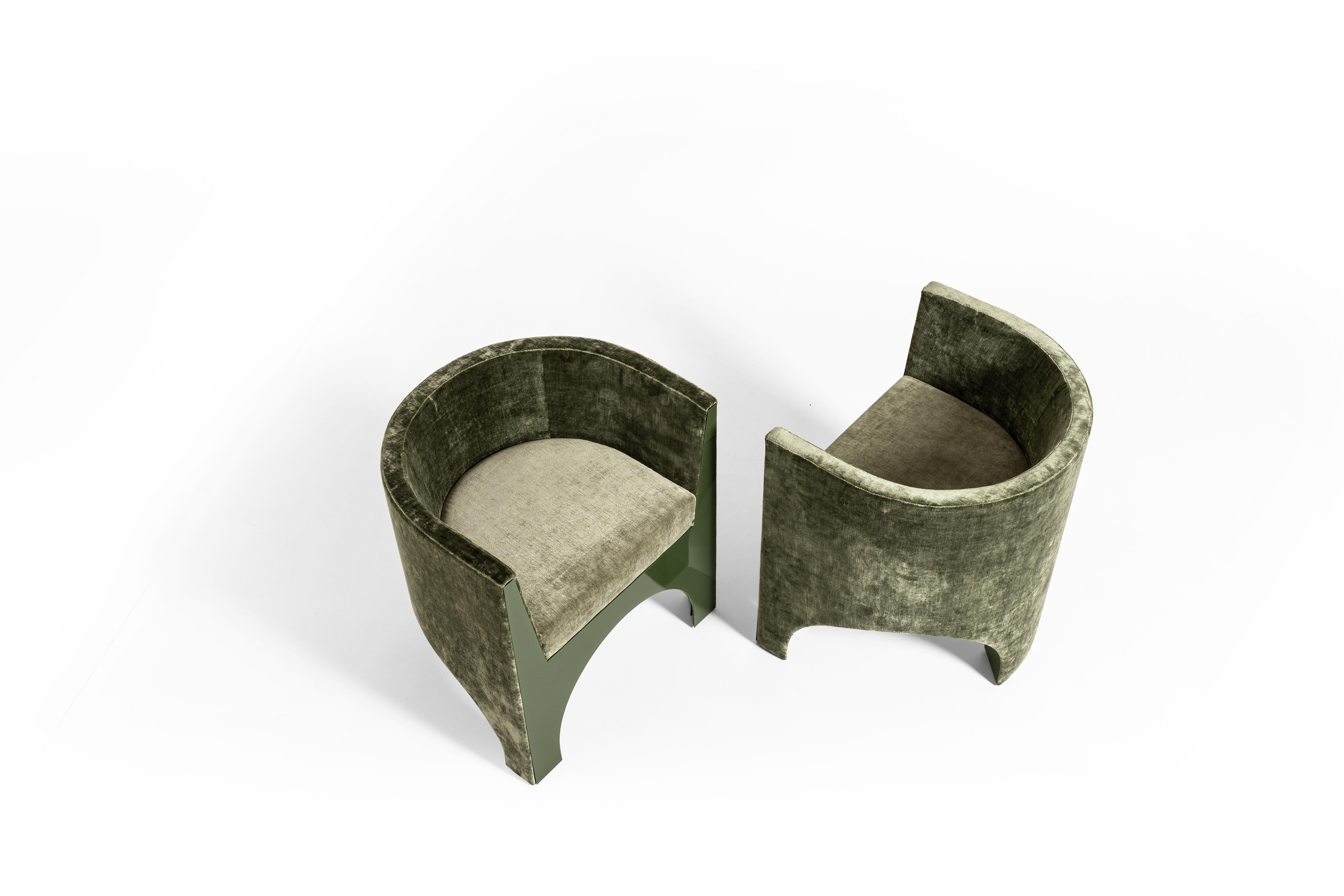 Revêtu de velours et doté d'une base et d'une façade vertes laquées brillantes, le fauteuil Volta s'inspire du langage architectural des arcs et des voûtes d'arêtes, en le réinterprétant avec une structure en bois courbé, où de véritables voûtes