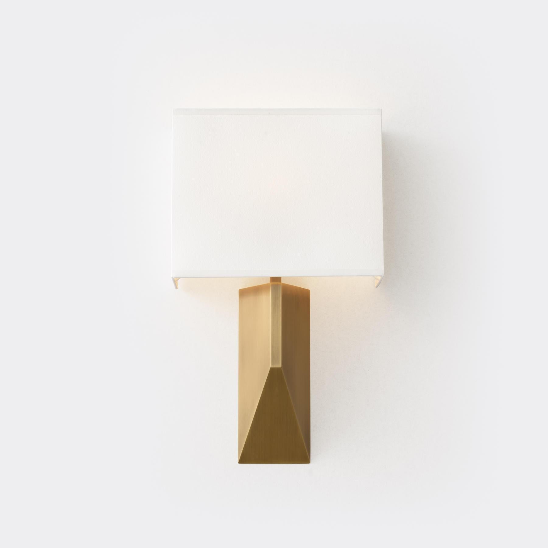Our Volume Sconce is a statuesque design with a substantial architectural base that appears as a revised pyramid when viewed in profile. It is topped by a three-sided aquarelle shade, allowing for tight mounting to a wall.