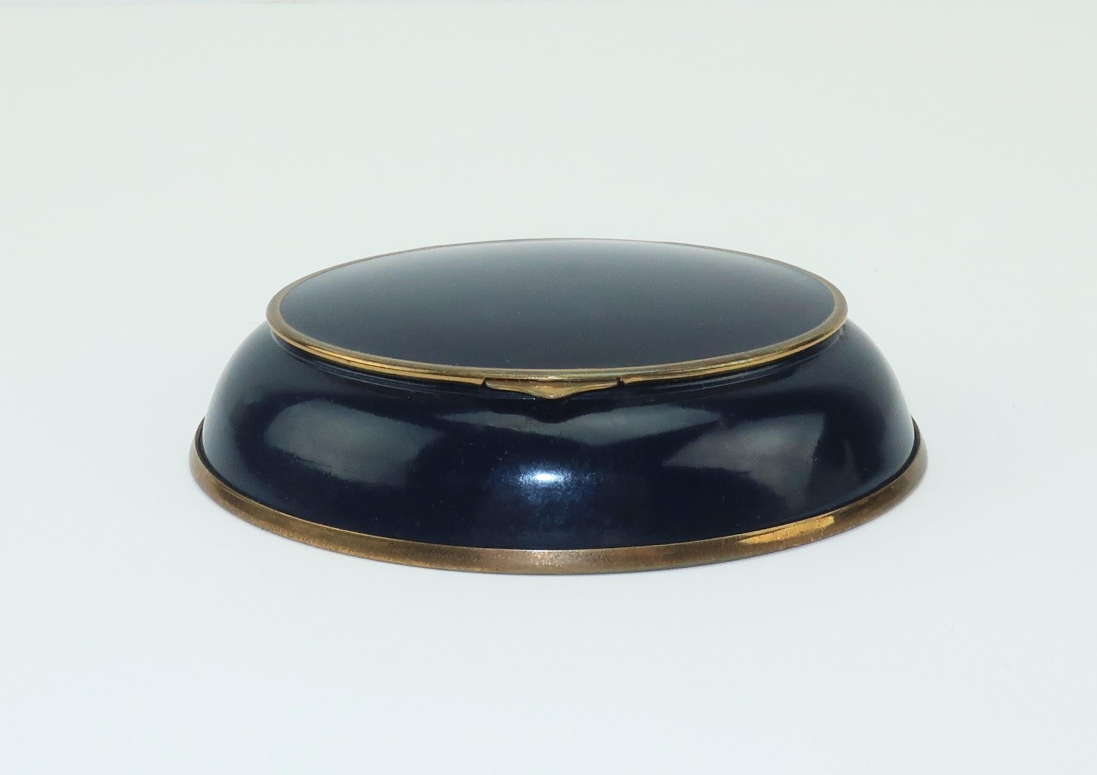 Volupte, an American company renowned in its day for glamorous mirrored compacts, created this unusual midnight blue enamel compact in the 1940's.  Though it could be carried in a handbag, this style seems better suited for a vanity display as it is