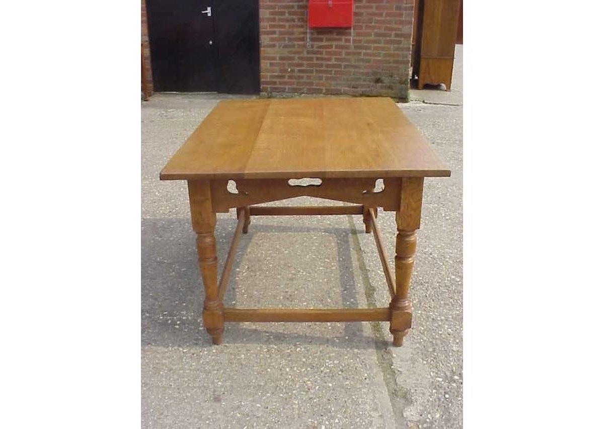 C F A Voysey in the style of.
An Arts & Crafts oak dining or library table with four stylized floral cut-outs flanked by dove cut-outs to each corner to the angled apron underneath the table top, on square and turned legs united by stretchers.