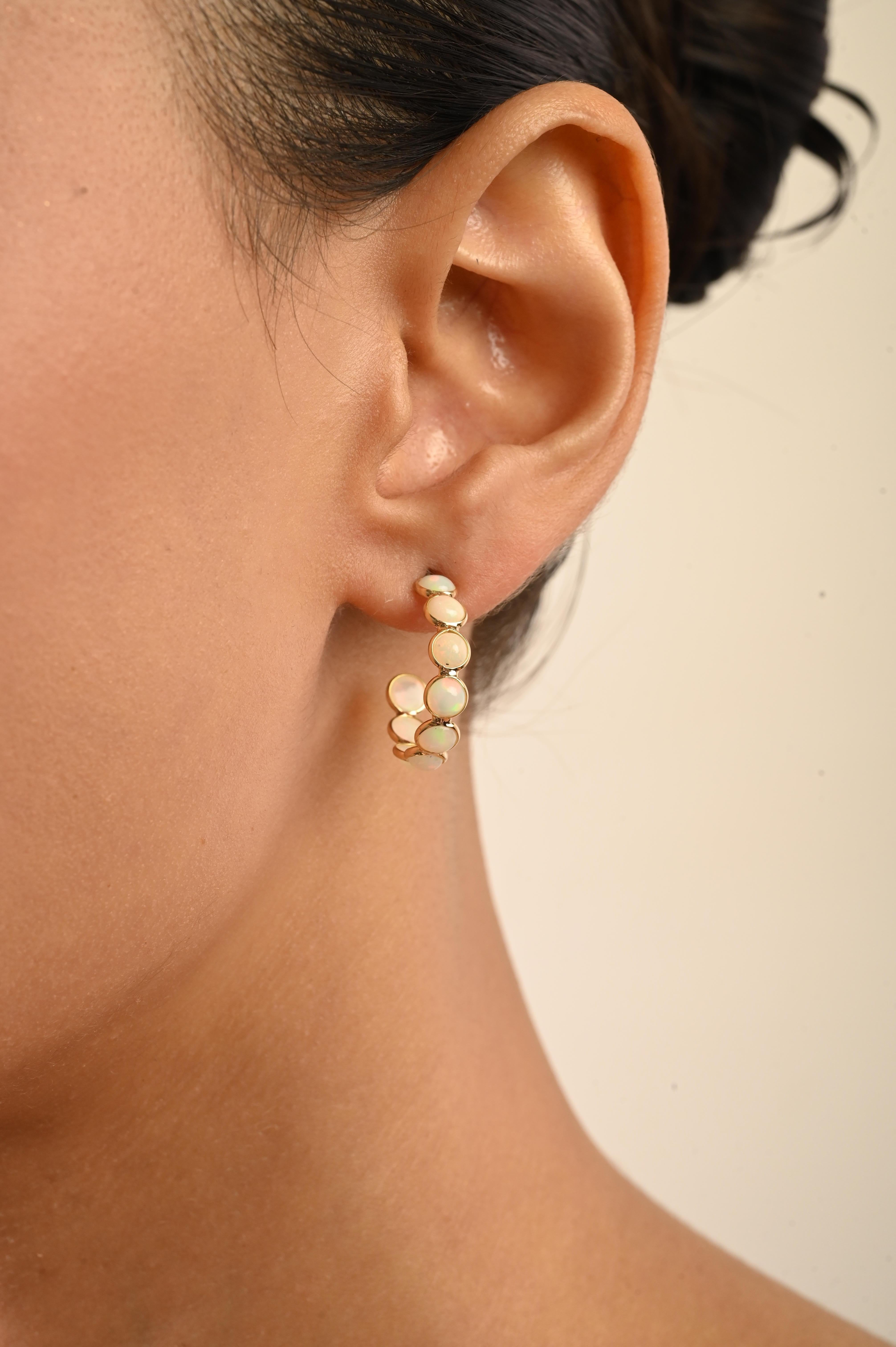 Ces élégantes boucles d'oreilles présentent un total de 2,82 carats d'opales naturelles rondes taillées en cabochon, magnifiquement serties dans un chaton en or jaune 18 carats. Chaque pierre précieuse mesure environ 3,9 mm de diamètre. Les boucles