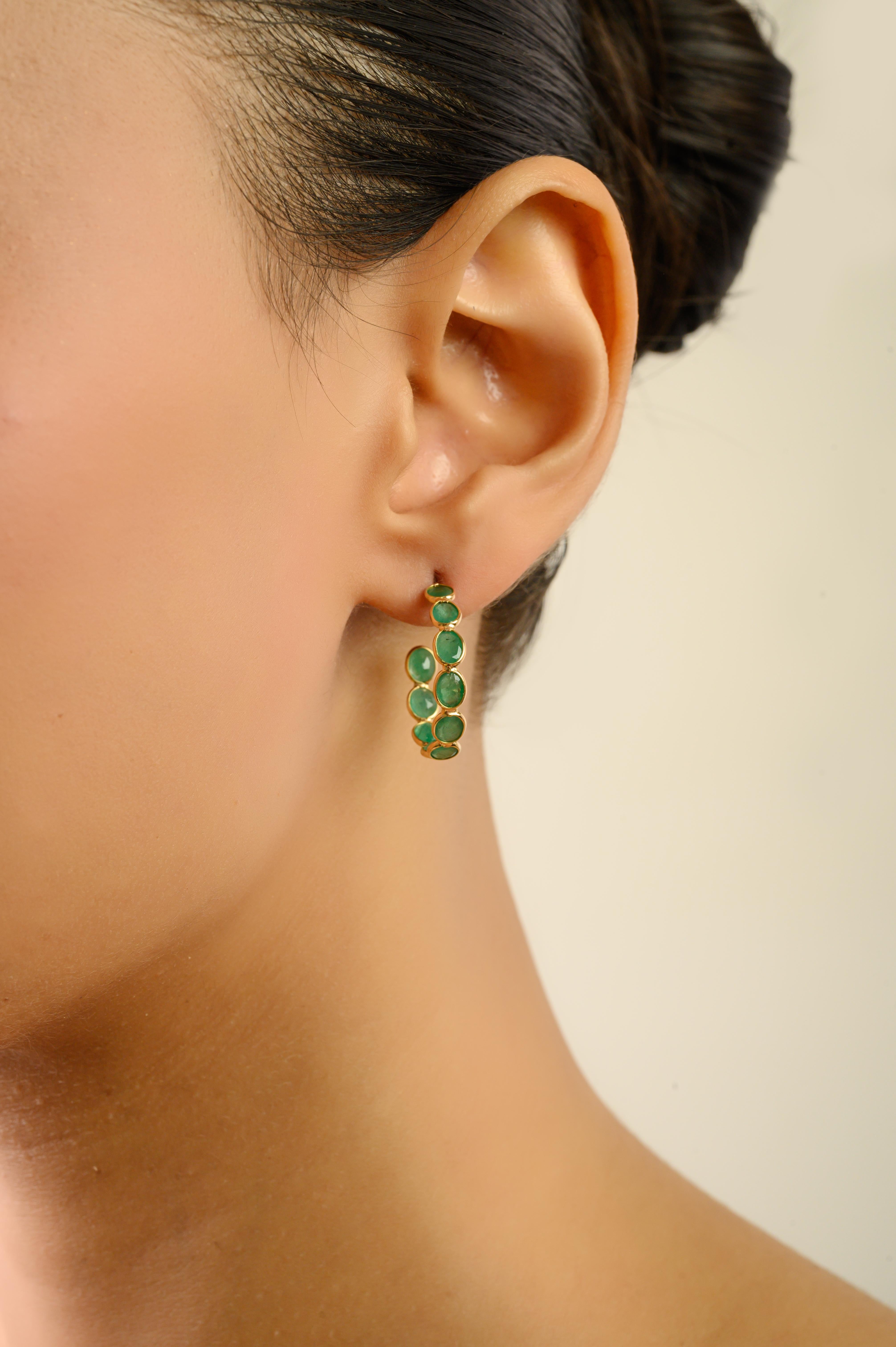 Ces élégantes boucles d'oreilles présentent un total de 4,20 carats d'émeraudes naturelles de taille ovale, chacune mesurant environ 3,5 x 2,9 mm, serties dans de l'or jaune 18 carats. Le design de l'anneau ouvert de style lunette maintient