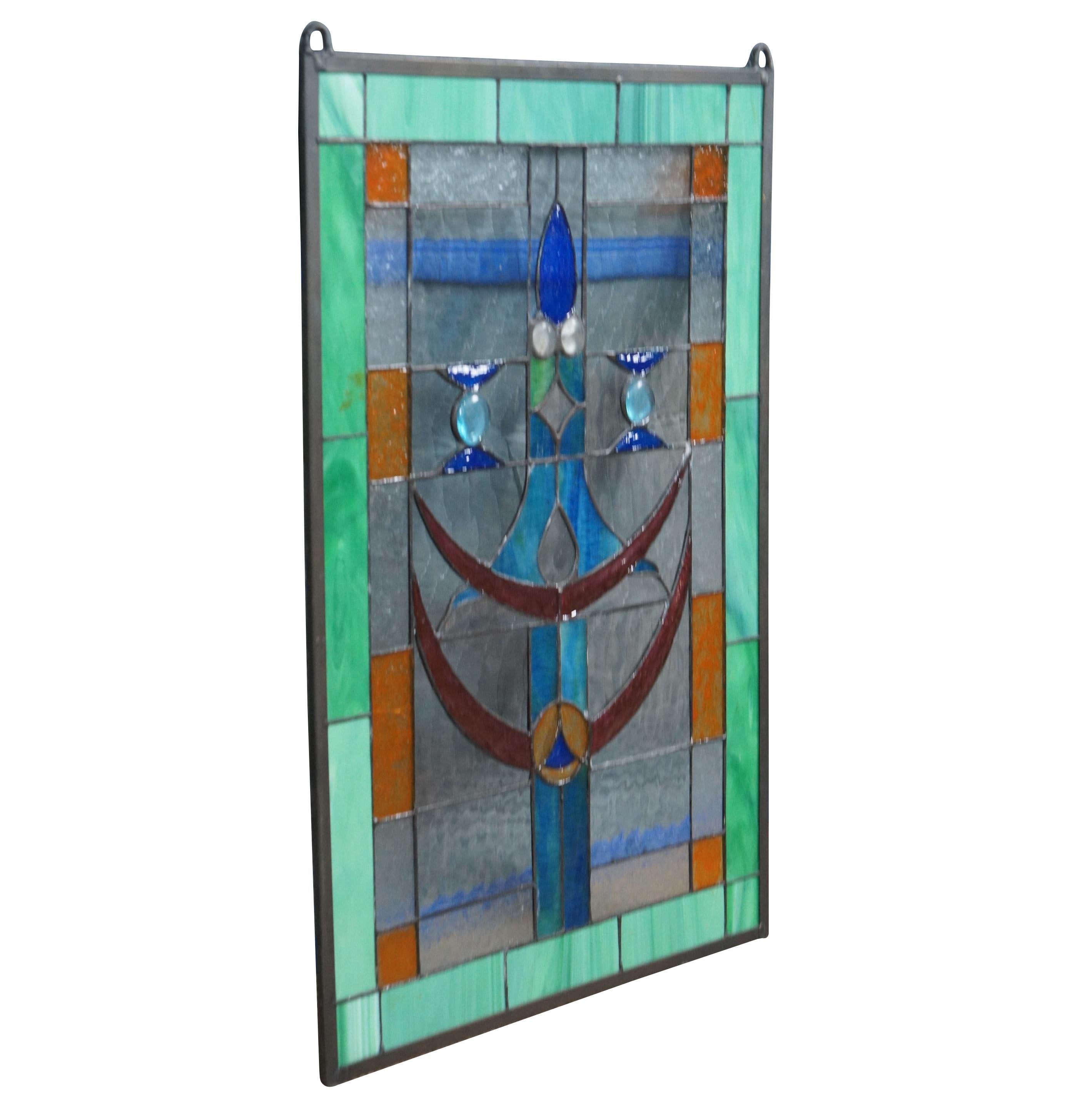 A beautiful leaded stained glass hanging panel. Features a Green border outside squares of amber, clear and a center of blues and ruby with beads. Elegant and clean lines will bring warmth to any room. Measure: 26