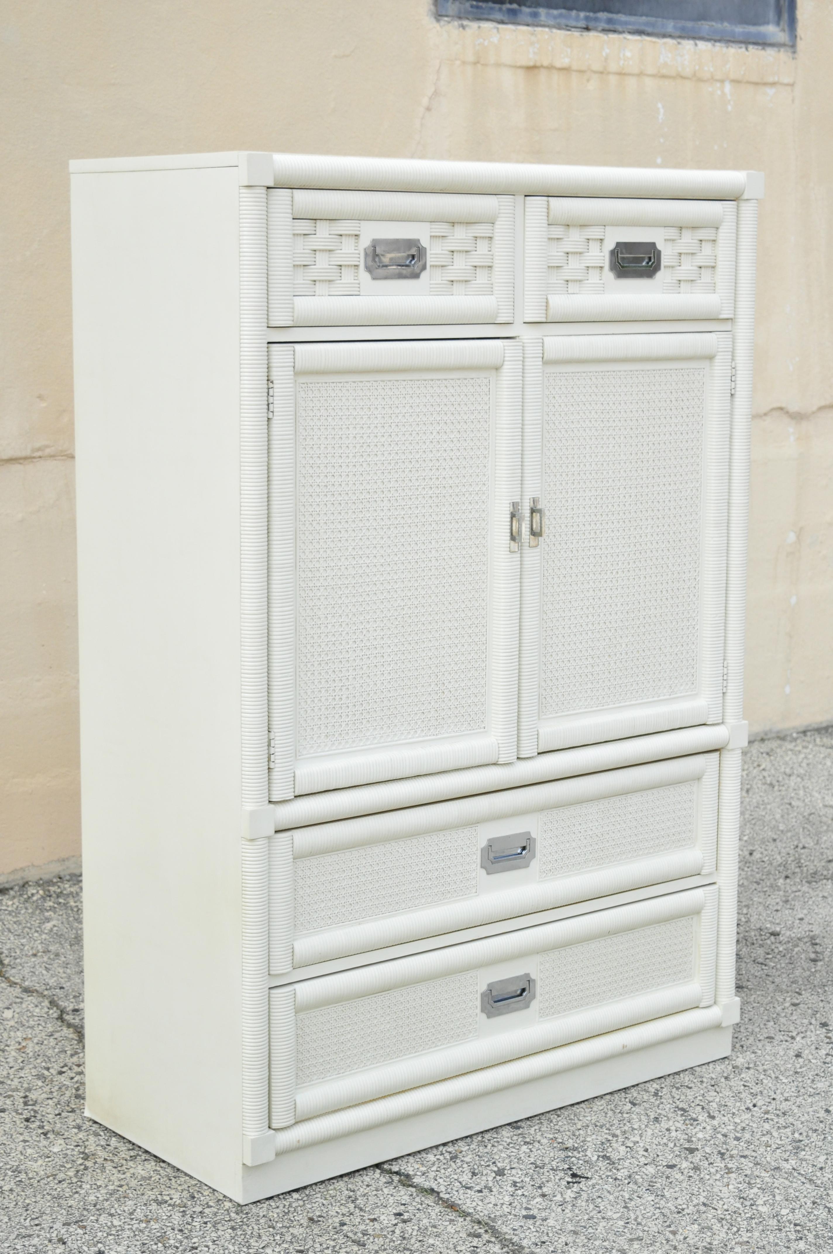 Vintage Dixie and cane rattan campaign style white tall chest armoire dresser cabinet. Item features a laminate top, chrome campaign style handles, rattan and cane front, white or cream lacquer finish, 2 swing doors, 5 dovetailed drawers, original