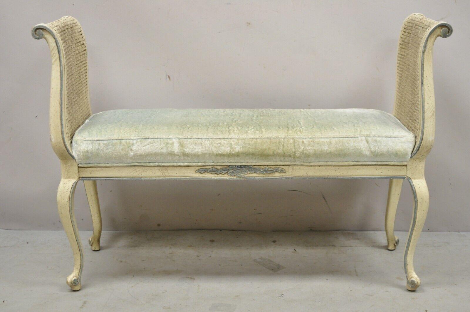 Vintage French Provincial Style Cream Painted Cane Cabriole Leg Window Bench with Arms. Item features cane side panels, cream painted finish, blue upholstery, solid wood frame, cabriole legs, great style and form. Circa Late 20th Century.