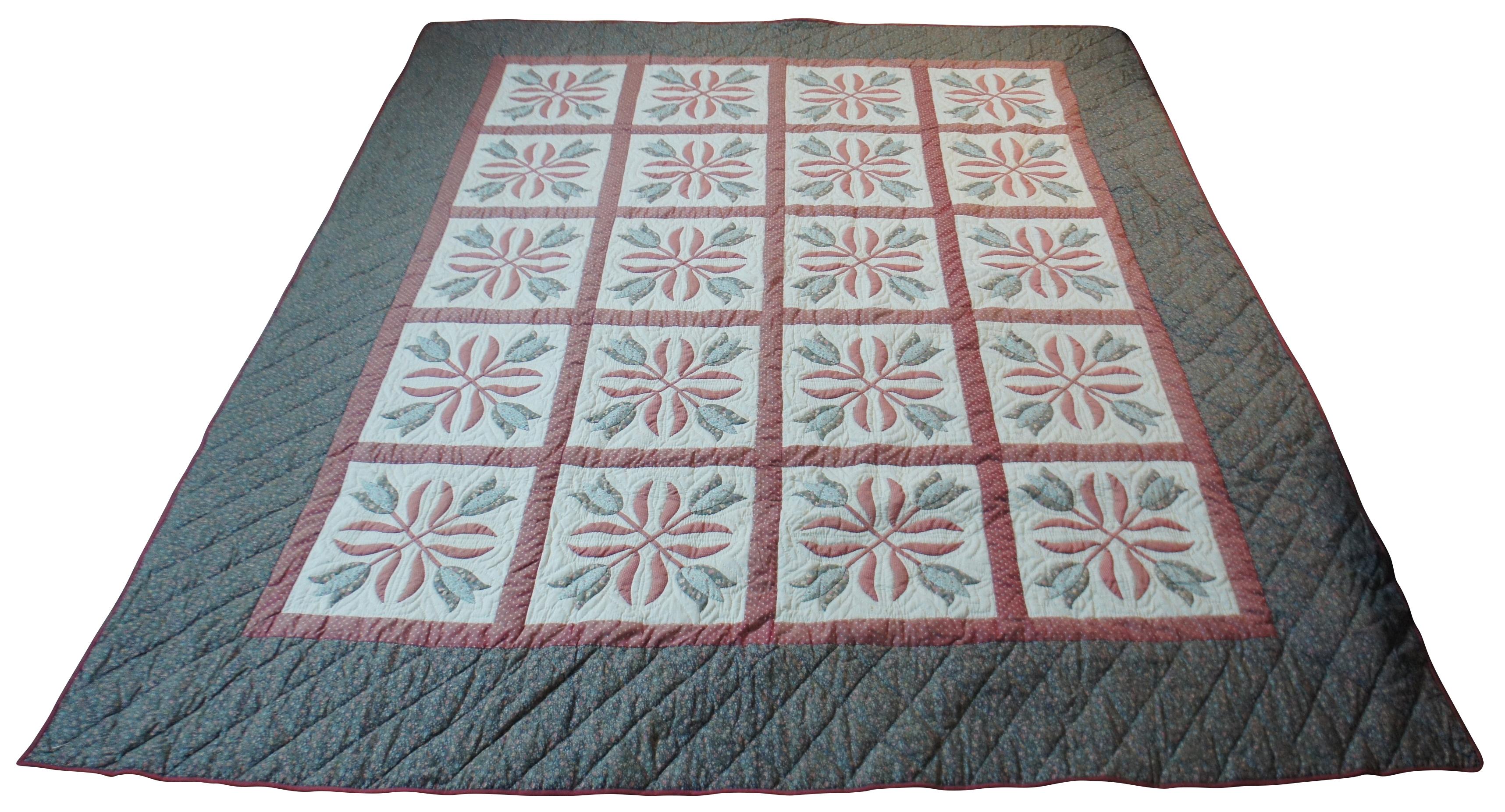 Vintage hand stitched king sized quilt featuring gray-green, mauve and white floral cotton in blocks framing quartets of tulips on the front, a navy blue floral back, and a curtain rod pocket along one edge for using the quilt as a wall hanging.