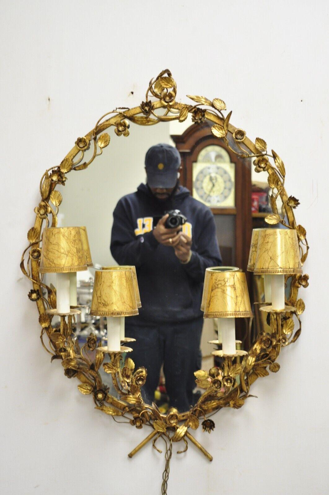 Vintage Italian Hollywood Regency Gold Gilt Iron Oval Floral Wall Mirror with Sconces. L'article présente un miroir central ovale, (4) appliques électrifiées, des cadres en fer doré, des accents feuillus, un très bel article vintage, un style et une