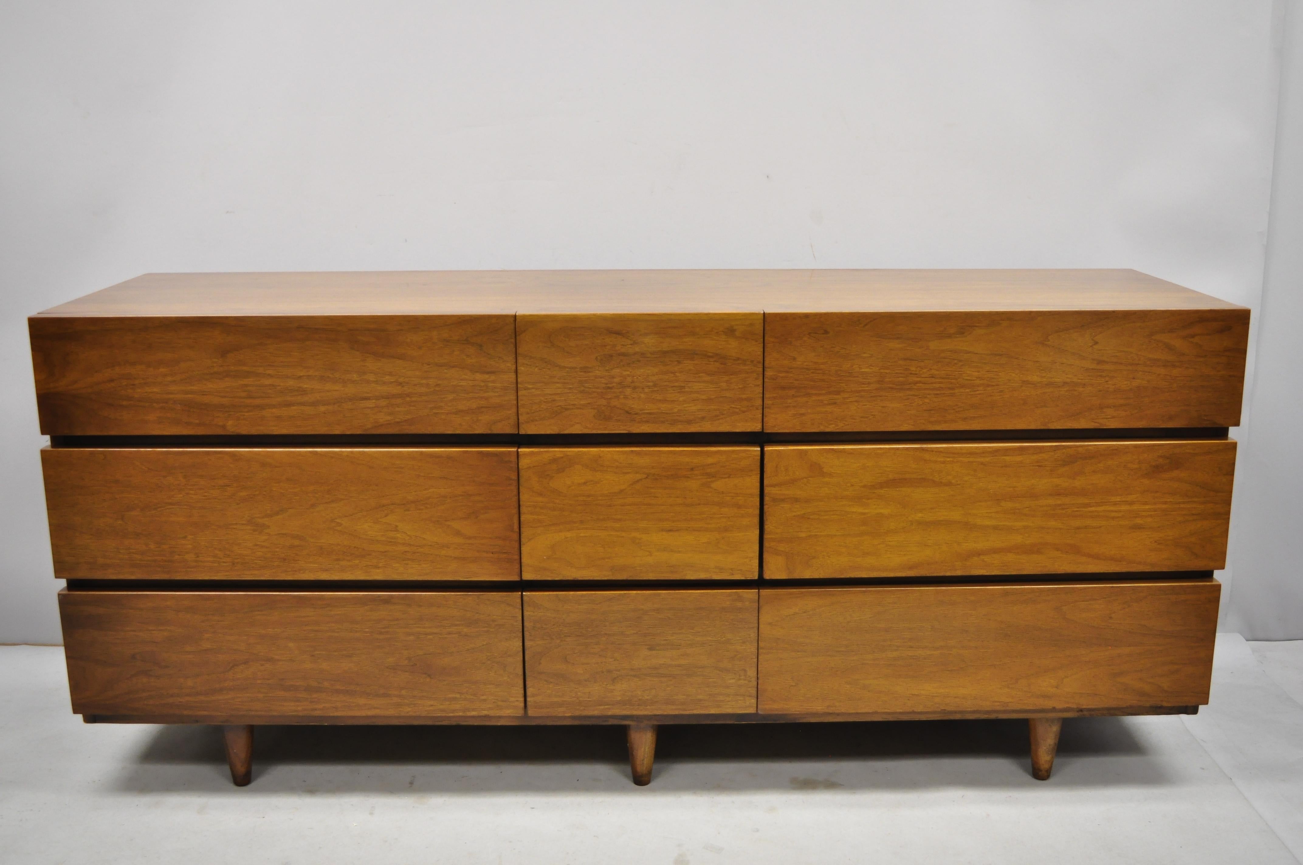 Vintage Mid-Century Modern American of Martinsville walnut long dresser credenza and mirror. Item includes beautiful wood grain, 9 drawers, tapered legs, very nice vintage item, clean modernist lines, circa mid-20th century.
Dresser: 31