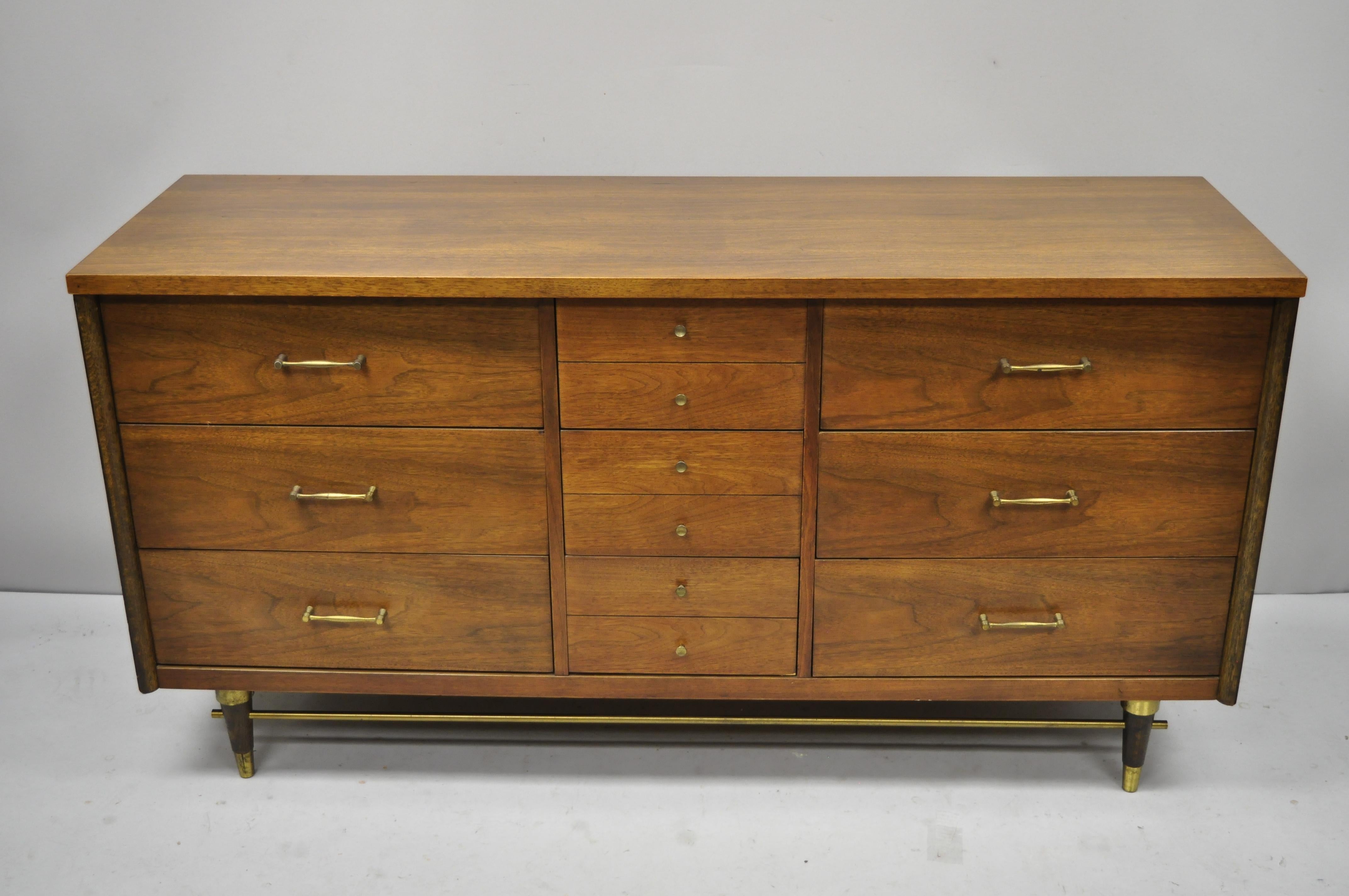 Vintage Mid-Century Modern walnut credenza with brass stretcher by Bassett. Item features beautiful wood grain, brass accents, original stamp, 9 dovetailed drawers, tapered legs, brass hardware, very nice vintage item, clean modernist lines, circa