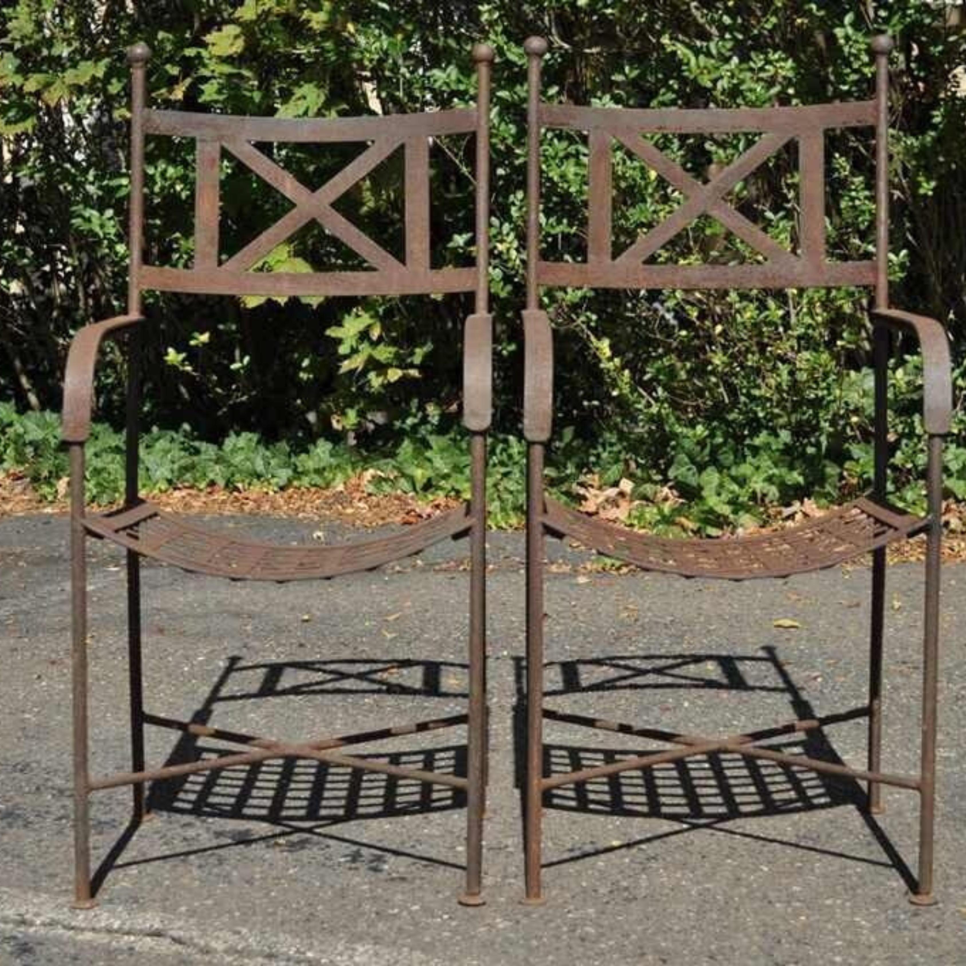 Vintage Neoclassical Regency Style Iron X Form Stretcher Garden Arm Chairs - a Pair. Item featured has sturdy construction with x-form stretcher base, riveted slat seats, weathered finish, very nice vintage set. Circa Early to Mid 1900's.