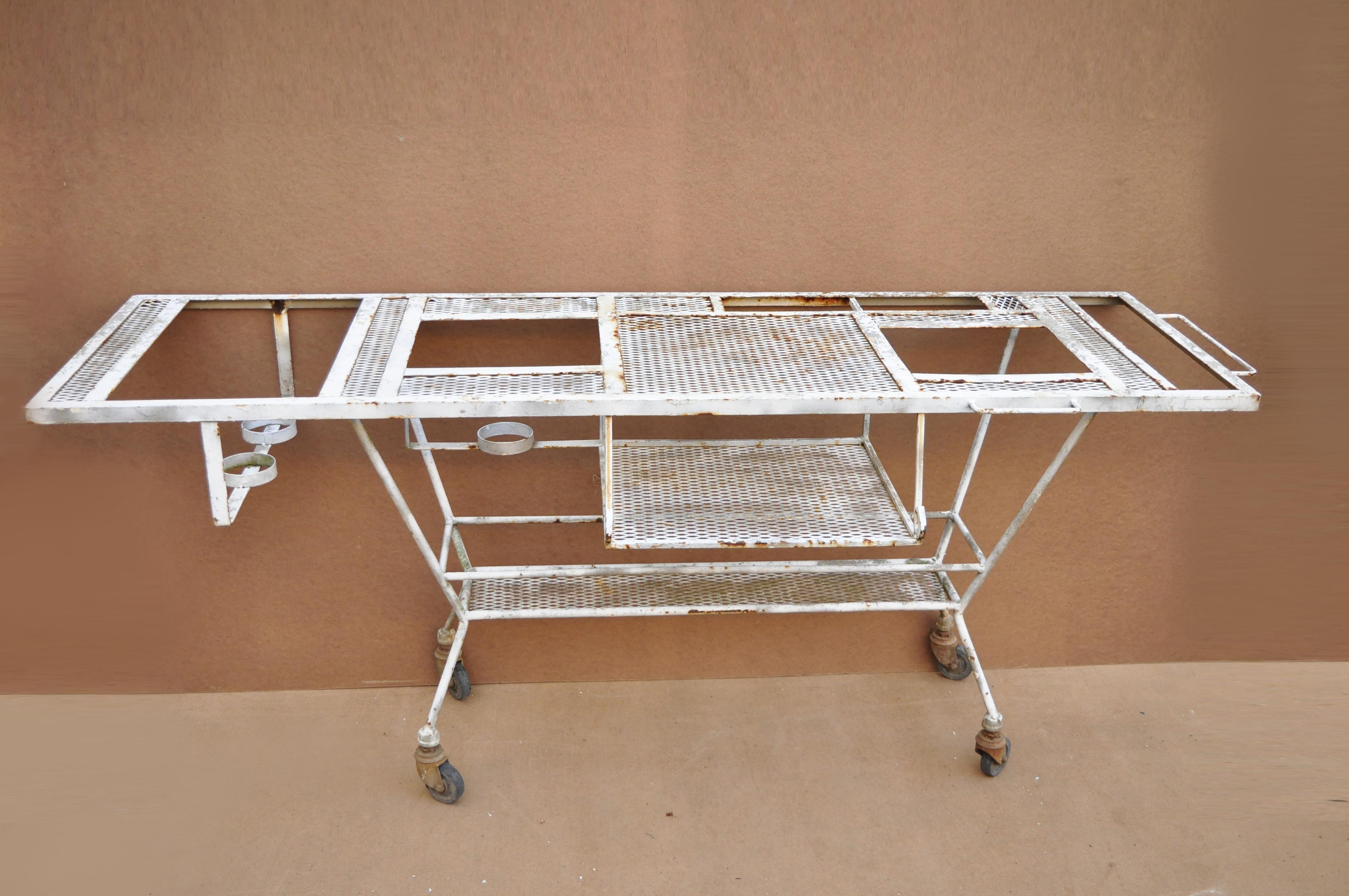 Vintage wrought iron industrial steampunk rolling bar cart barbeque pit table. Item features various compartments, rolling wheels, mesh surfaces, side handle, wrought iron construction, great style and form, original use is unknown but great to
