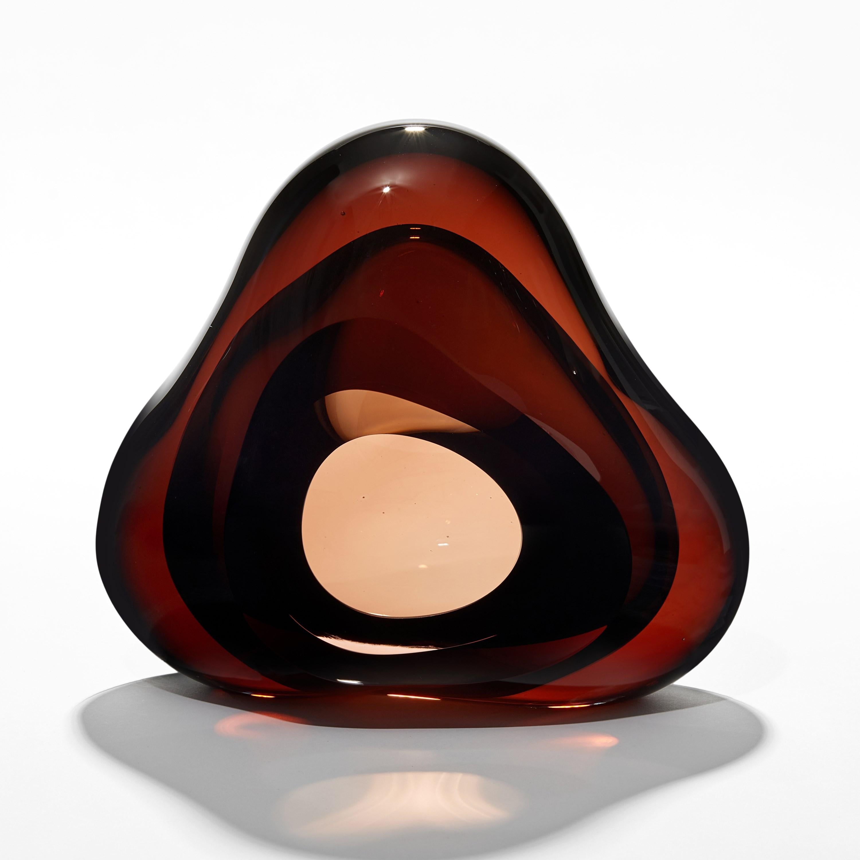 'Vug in Dark Amber & Olive Green' is a unique handblown sculpture by the British artist, Samantha Donaldson.

Created by layers of coloured glass, the transparent colours merge and create further hues throughout the piece. An additional optical