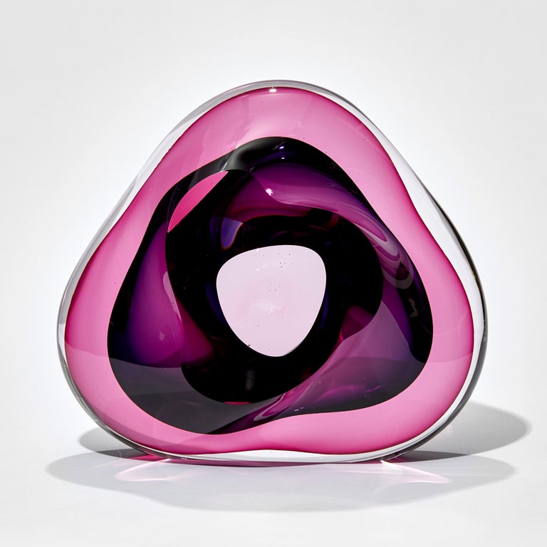 Vug in Fuchsia and Purple is a unique hand-blown sculpture by the British artist Samantha Donaldson. Created by layers of colored glass in bright pink and purple, the transparent colors merge and create further hues throughout the piece. An