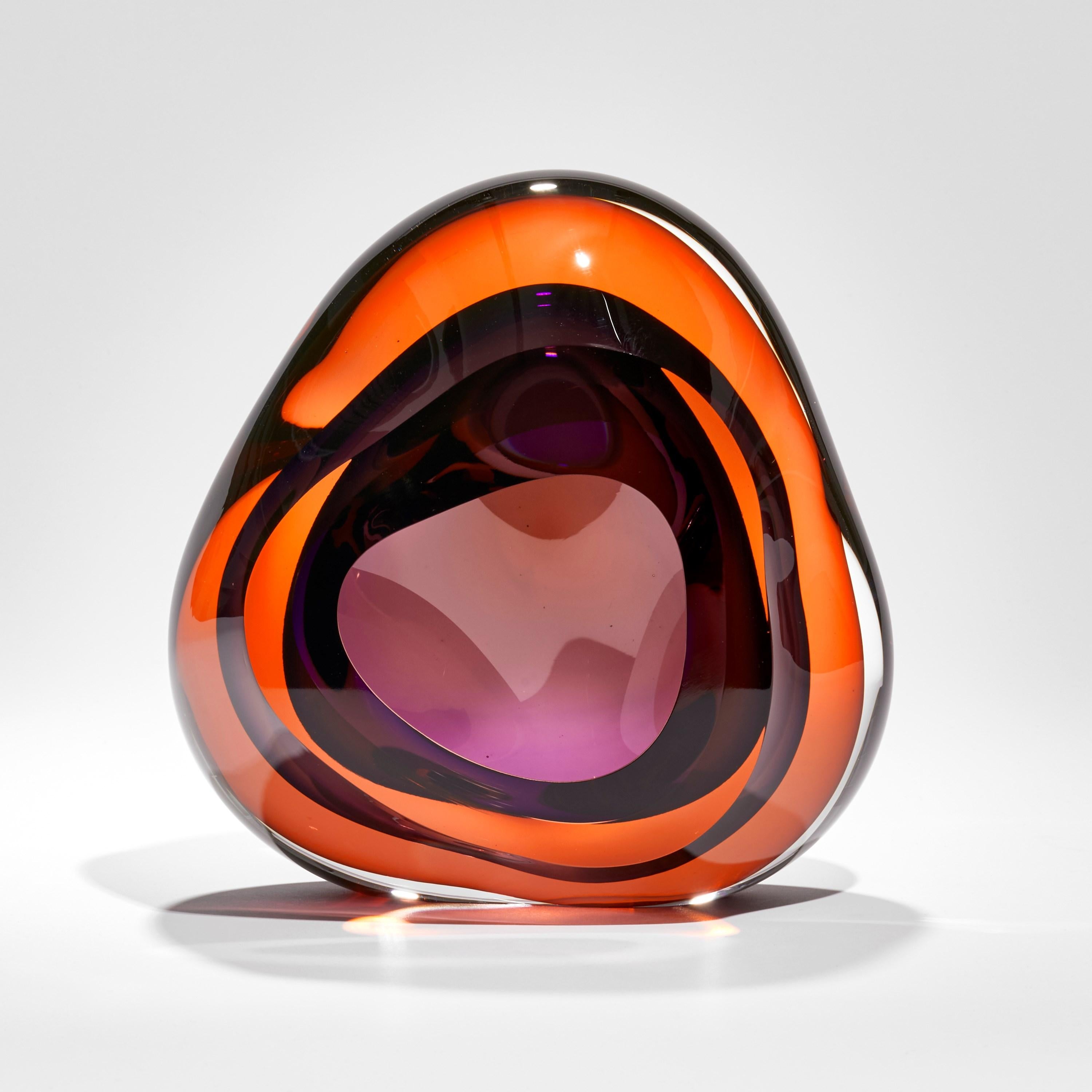 'Vug in Orange and Purple' is a unique handblown sculpture by the British artist, Samantha Donaldson. Created from layers of coloured glass in intense orange and rich purple, the transparent colours merge and create further hues throughout the