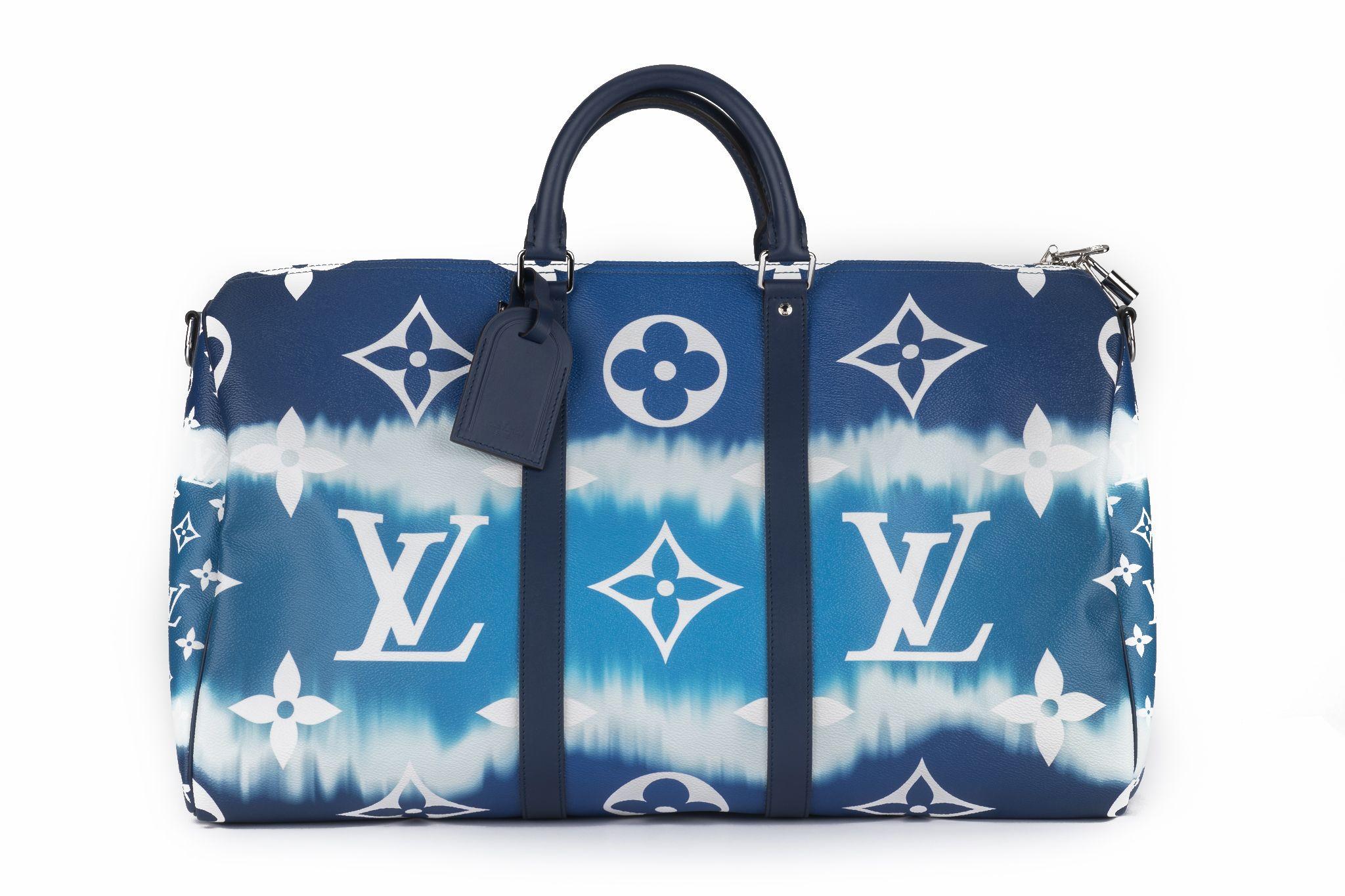 This Louis Vuitton Monogram Escale Keepall Bandouliere 50 in blue is crafted of Louis Vuitton monogram on toile-coated canvas and features a watercolor print, leather trim including rolled top handles and a removable shoulder strap. The silver top