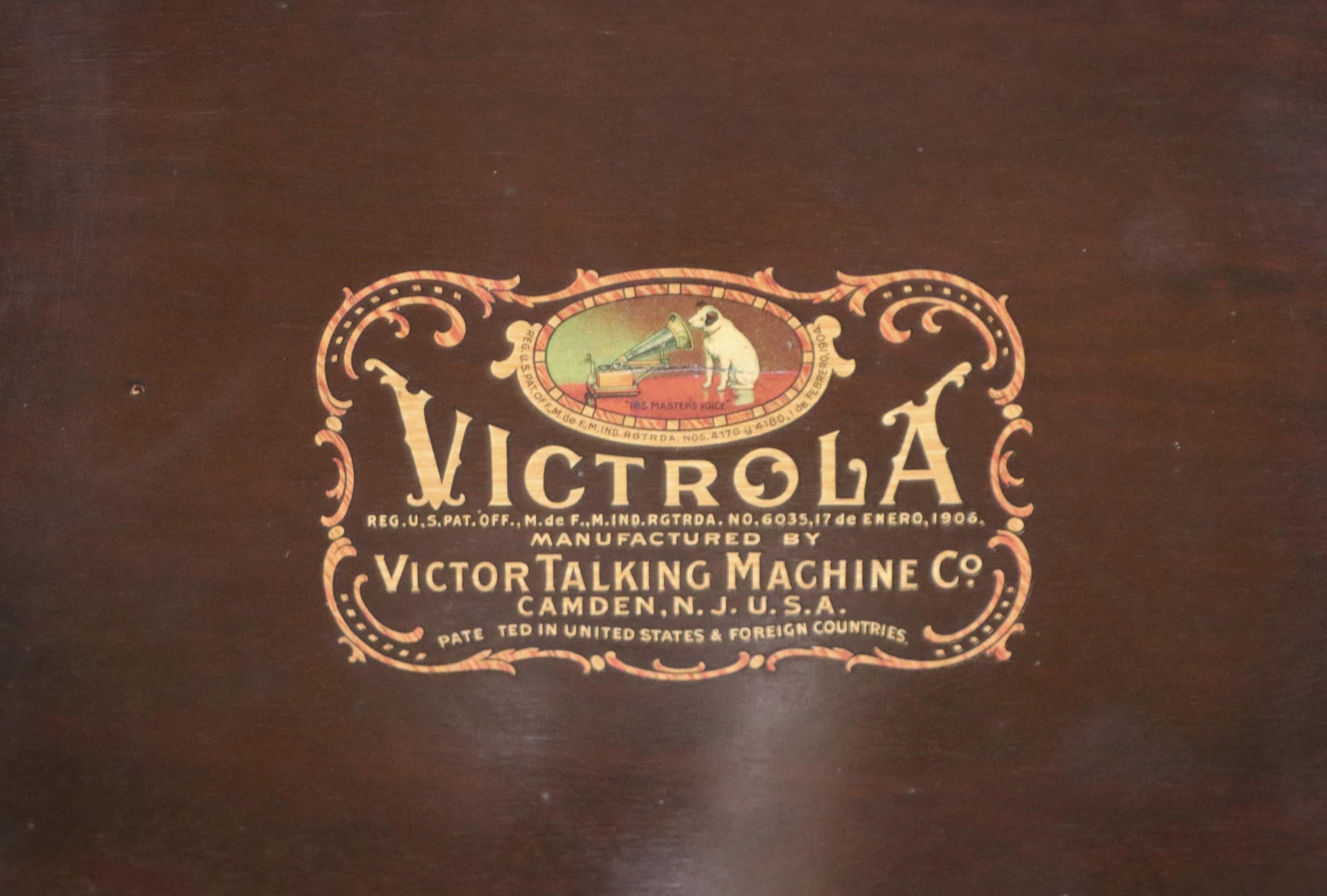 Antiker Victrola Phonograph VV-80 Standmodell. Es wurde von The Victrola Victor Talking Machine Company hergestellt, Modell VV-80 155529.  Der Phonograph hat ein dunkel getöntes Holzgehäuse mit einem Holzdeckel darunter. Diese Victrola Victor