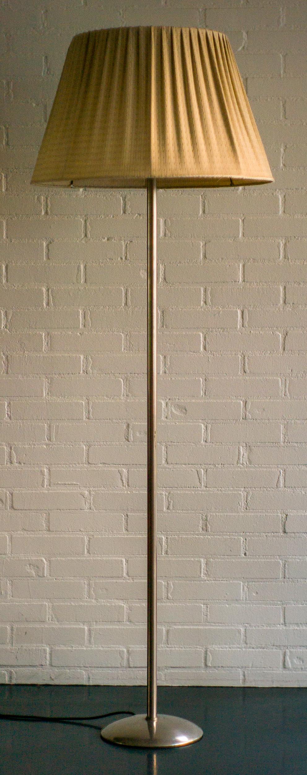 Modernist nickel-plated steel floor lamp with the original fabric shade.
The lamp has one uplighter and two lamps shining down.
Both the uplighter and the two downward lights have a separate light switch.
In wonderful all original