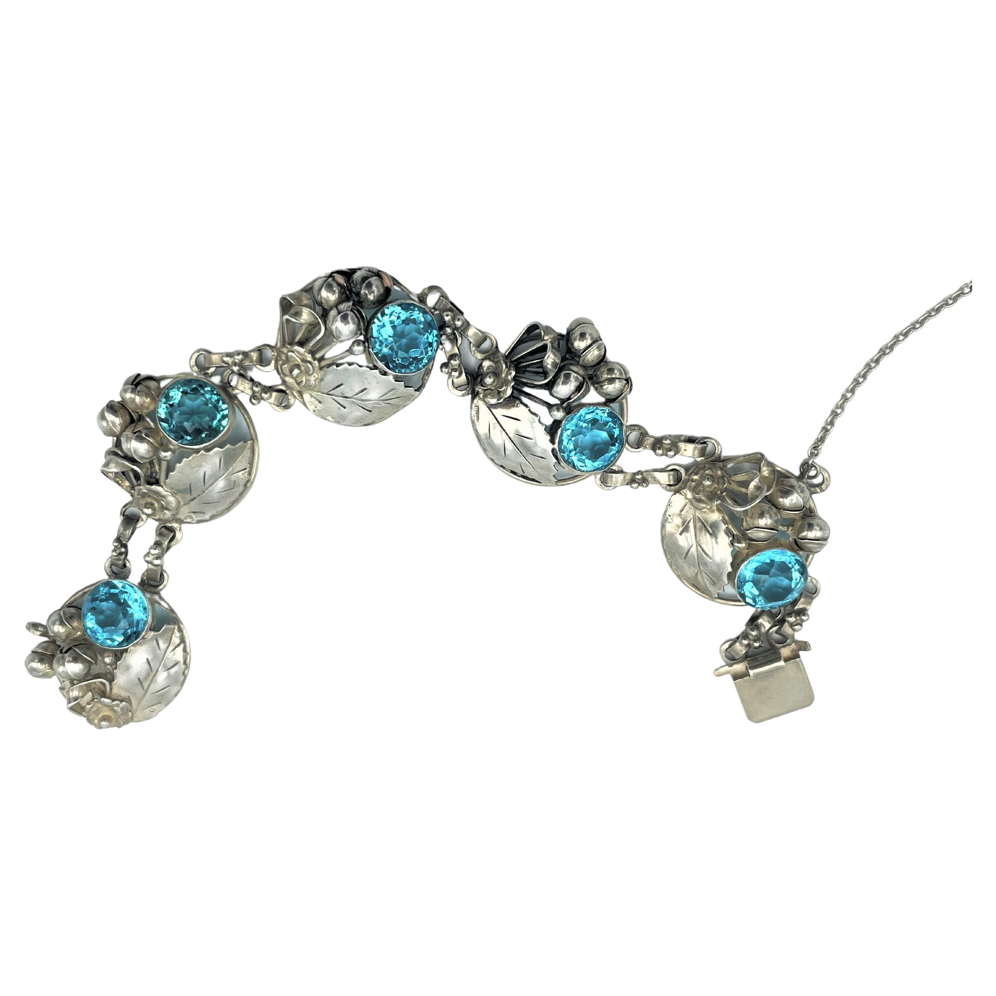 Vintage Bracelet by Hobè NY handcrafted bracelet consisting of 5 round flower bouckets  and a large cut aqua rhinestone. Worked in silver, signed Hobè on die claps in the 1940s USA. 

Measurements: Length 20 cm, Width 2,8 cm, every round boucket 2,8