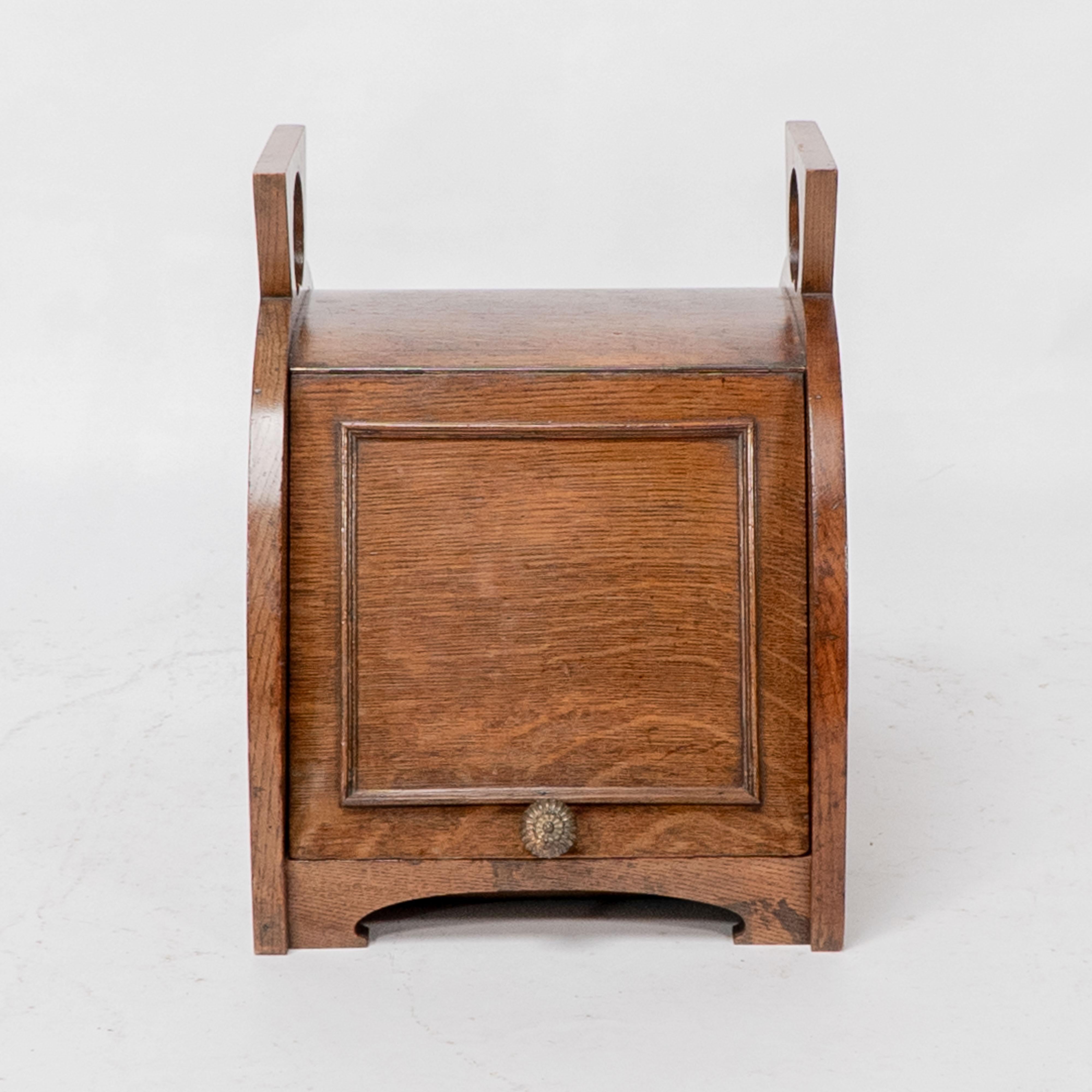 W J Neatby attributed. An Arts and Crafts oak coal box with stylized carrying handles to the top of angular form.