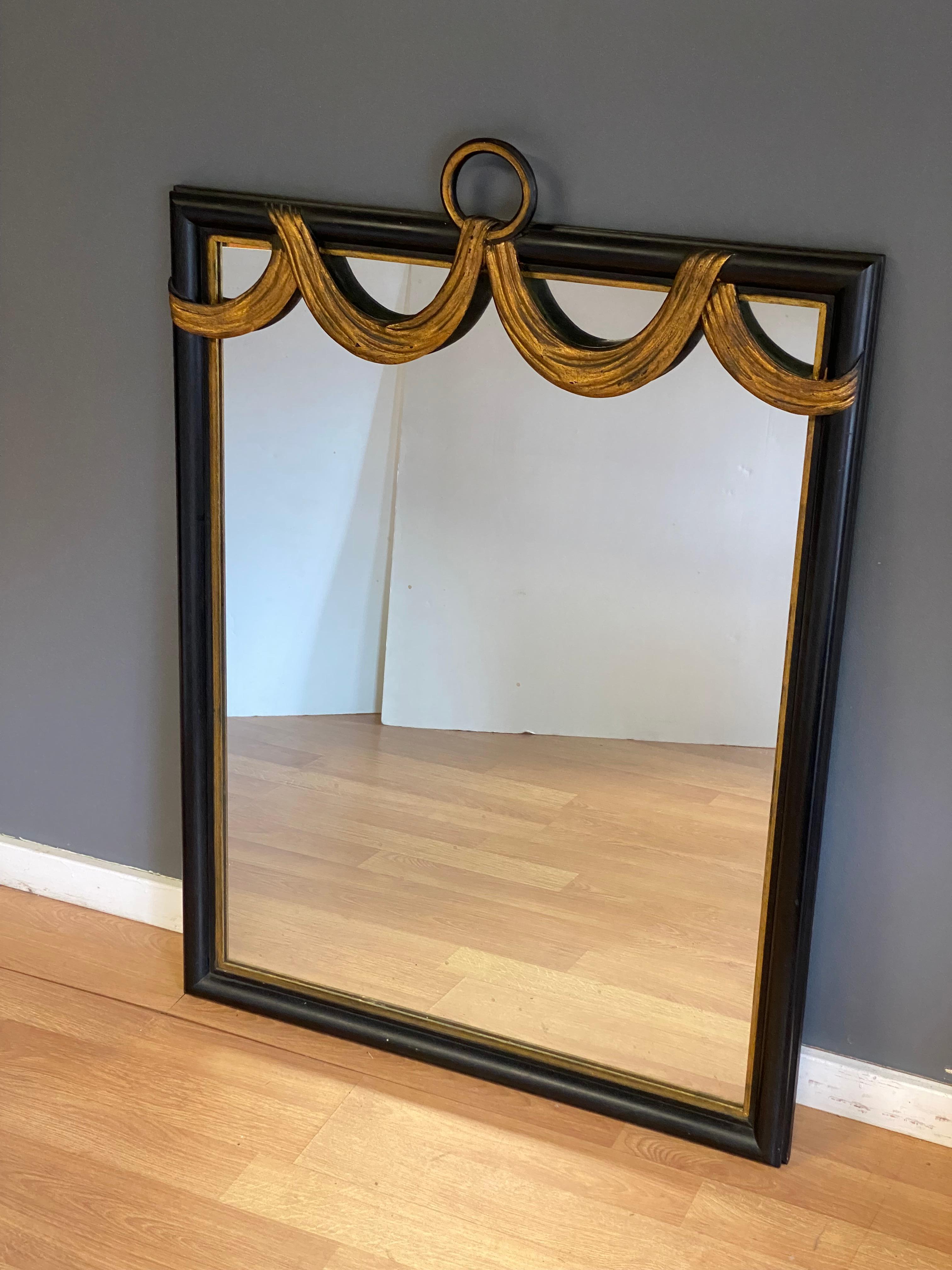 The finest ebonized and parcel gilt swag decorated wall mirror. A truly distinct Hollywood Regency piece that retailed at the prestigious furniture department store, W & J Sloane. W & J Sloane is always indicative of quality and fine design. They