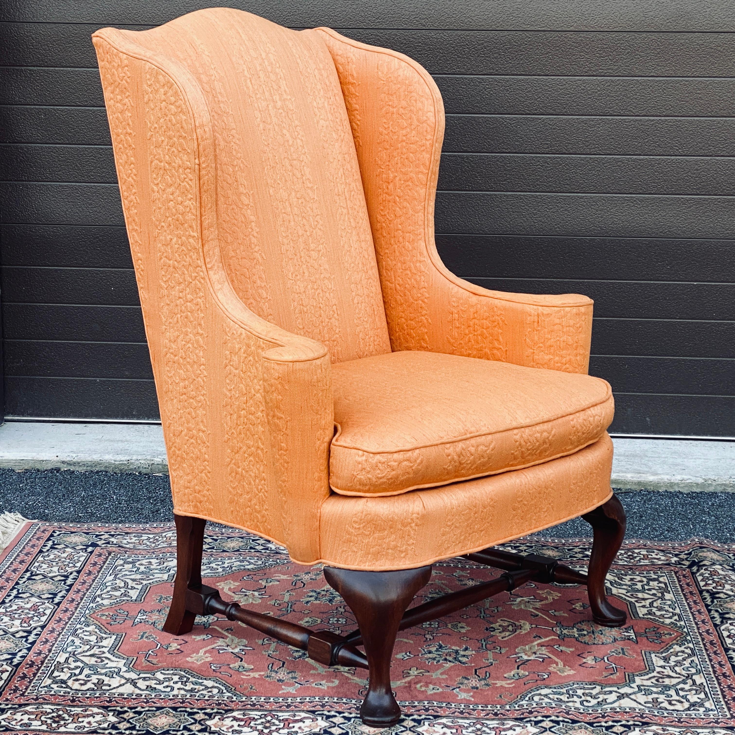 Vintage high end wingback chair from W. and J. Sloane Inc. Fifth Avenue New York, N.Y. with the original orange jacquard upholstery and solid mahogany legs with stretchers. Spring down and feather seat.