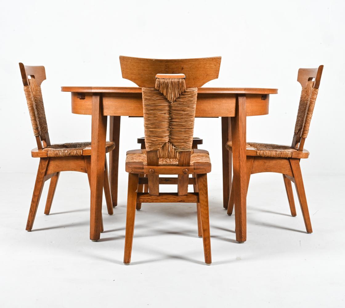 Presenting a fabulous and rare breakfast suite from the early days of Dutch design, with influences from the Arts and Crafts and Rationalist movements. Crafted from oak wood and woven seagrass rush, this suite includes (4) side chairs and an oval