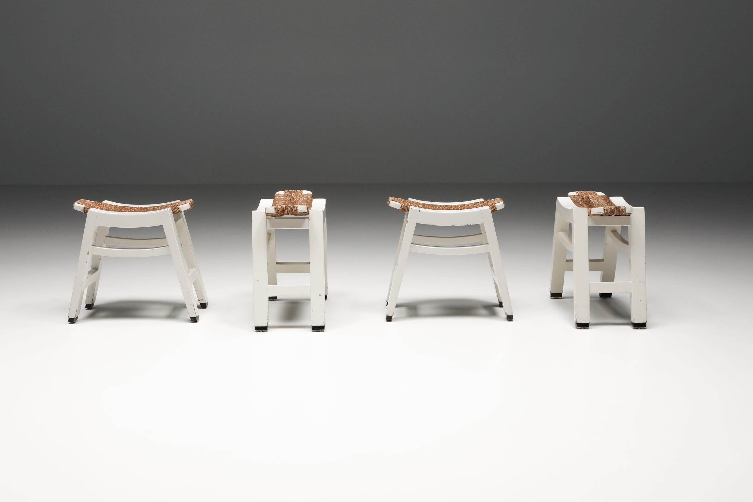 Set of four exquisite Dutch design white wooden stools with woven rush seating, artfully crafted in the style inspired by W. Kuyper. These stools present a captivating contrast, where the warm, earthy texture of brown rush seamlessly harmonizes with