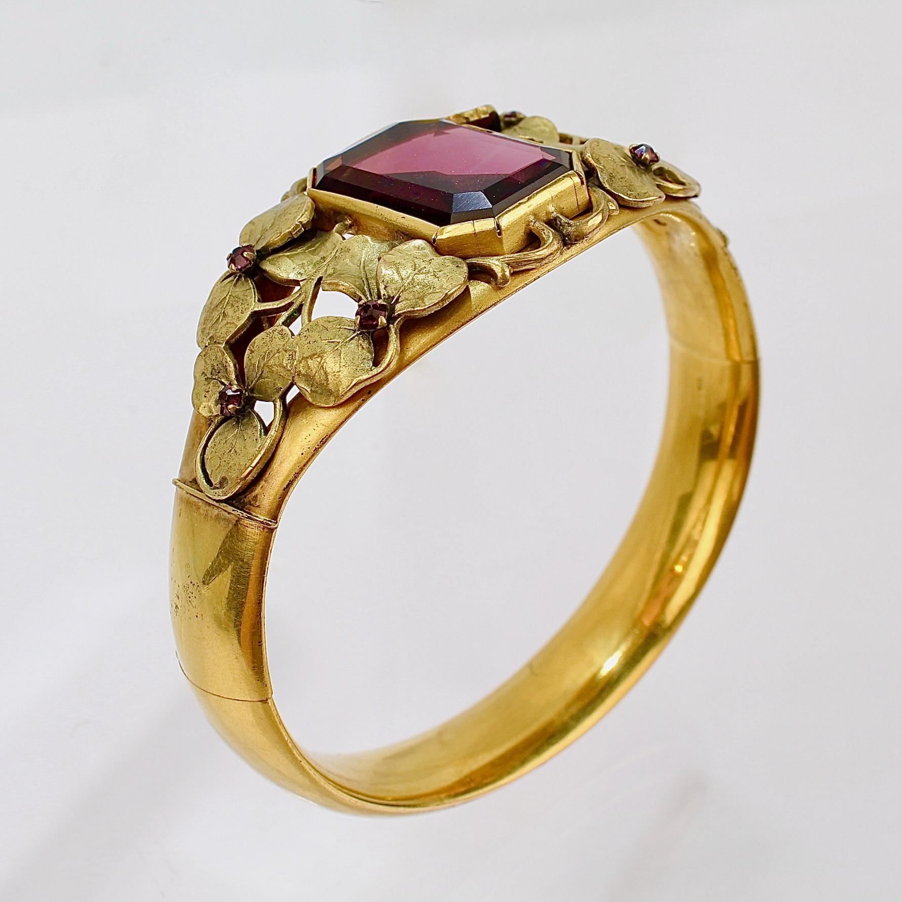 A very fine Victorian gold filled bangle bracelet.

Made by the W. & S. Blackinton Co. of Meriden, CT in the late 19th century.

The center is bezel set with an emerald-cut purple glass stone and surrounded with gold filled leaf work.  

The veined