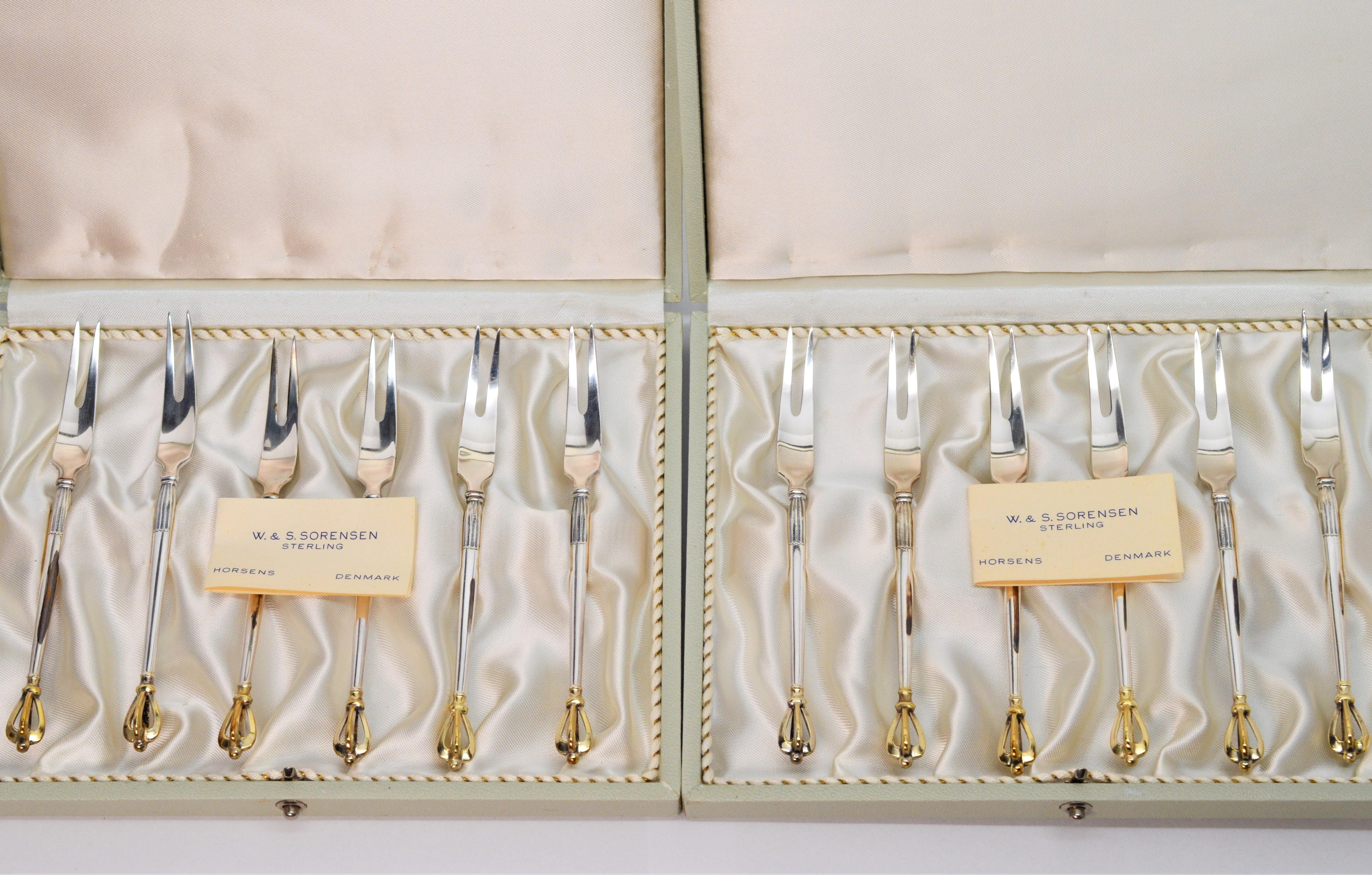 Unterhalten Sie stilvoll mit diesem eleganten Satz von zwölf Cocktailgabeln aus Sterlingsilber des dänischen Silberschmieds W. & S. Sorensen:: Horsens Dänemark. 
Das Set besteht aus zwölf feinen 4-1/4-Zoll-Sterlingsilber-Cocktailgabeln in ihren