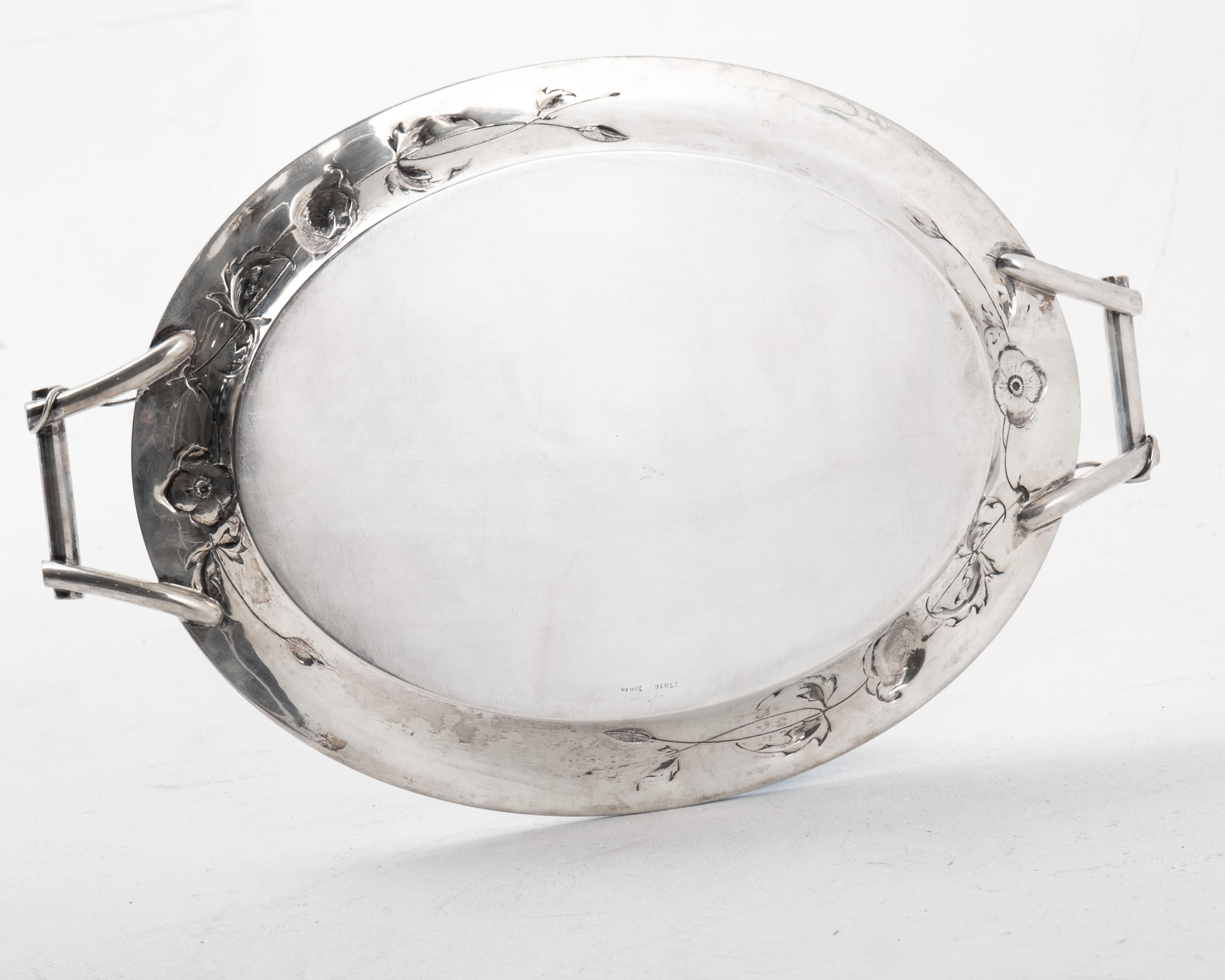 Eccezionale vassoio da portata in argento fine Art Nouveau, firmato W. Stüttgen, realizzato in Germania nel 1915 circa. Questo vassoio d'argento dell'800 ha una forma ovale con due manici decorativi e intricati motivi di fiori di papavero in