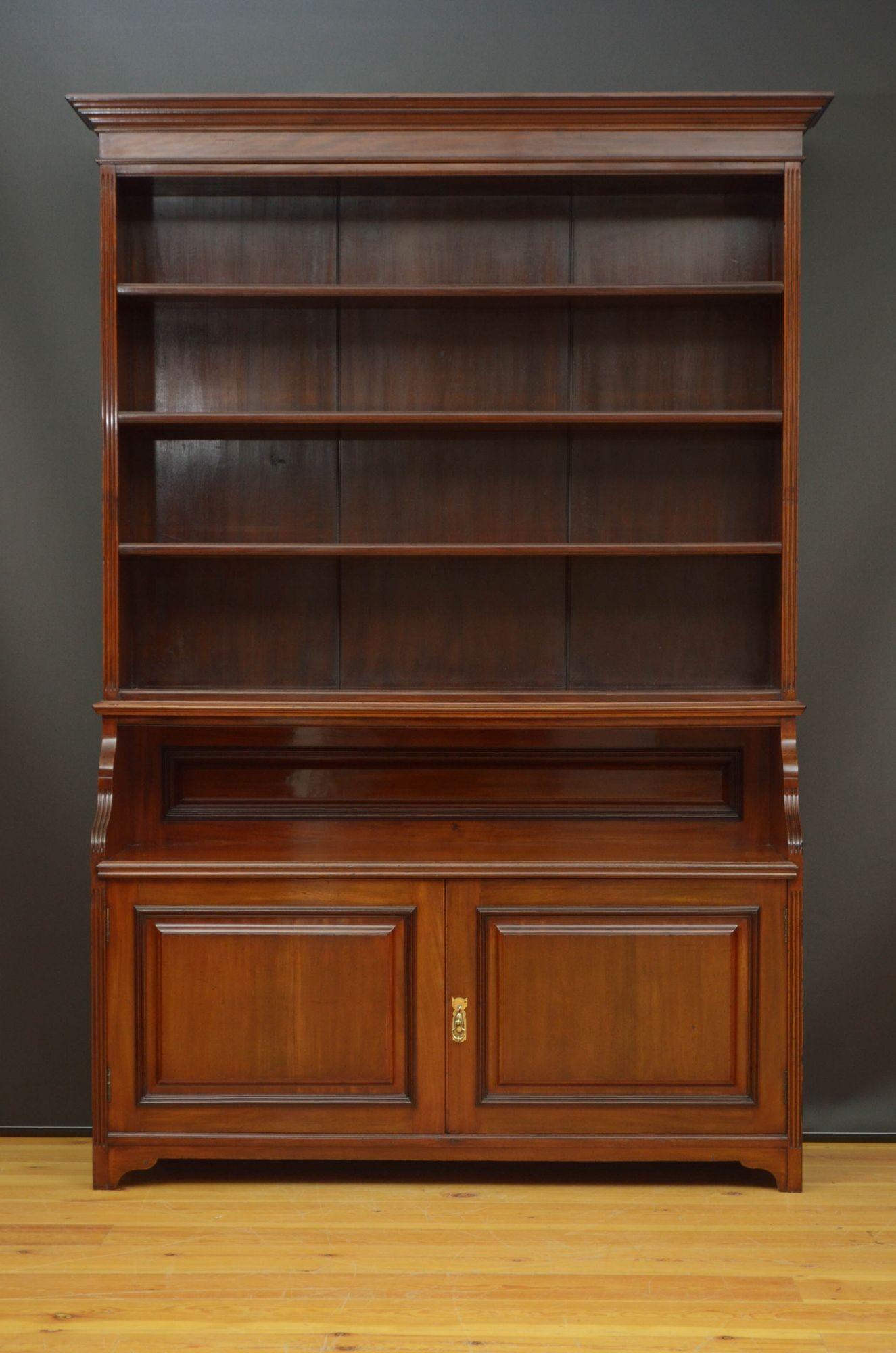 St022 A Late Victorian solid mahogany bookcase, having cavetto cornice above an open section with three height adjustable shelves, further deep open section and a pair of panelled cupboard doors fitted with working lock and a key, enclosing single