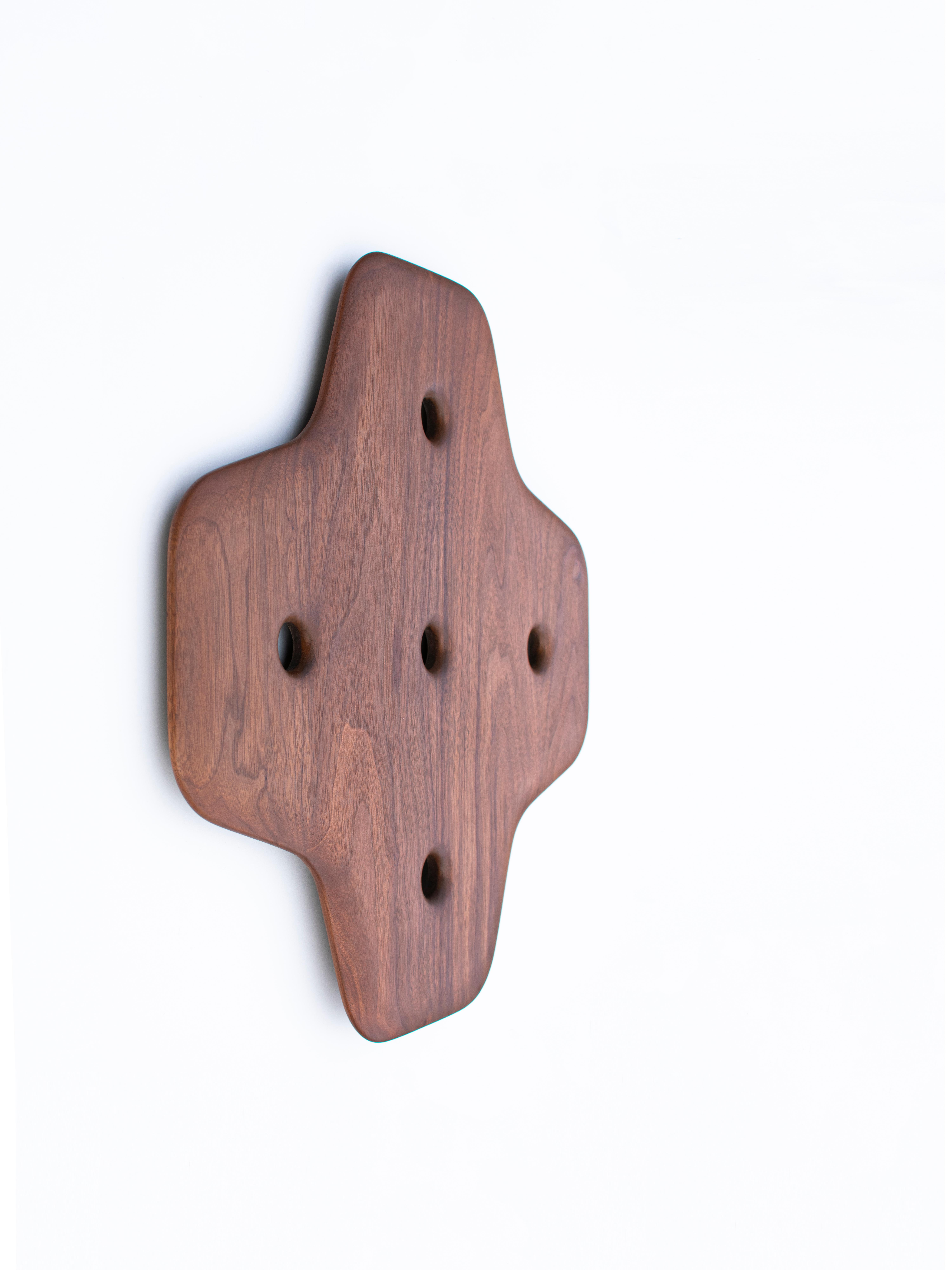 A modernist wall sculpture hand carved in walnut that embodies a captivating synthesis of form and emotion, inviting viewers into a journey of personal discovery. Its smooth surface finish, meticulously crafted, invites touch and exploration,