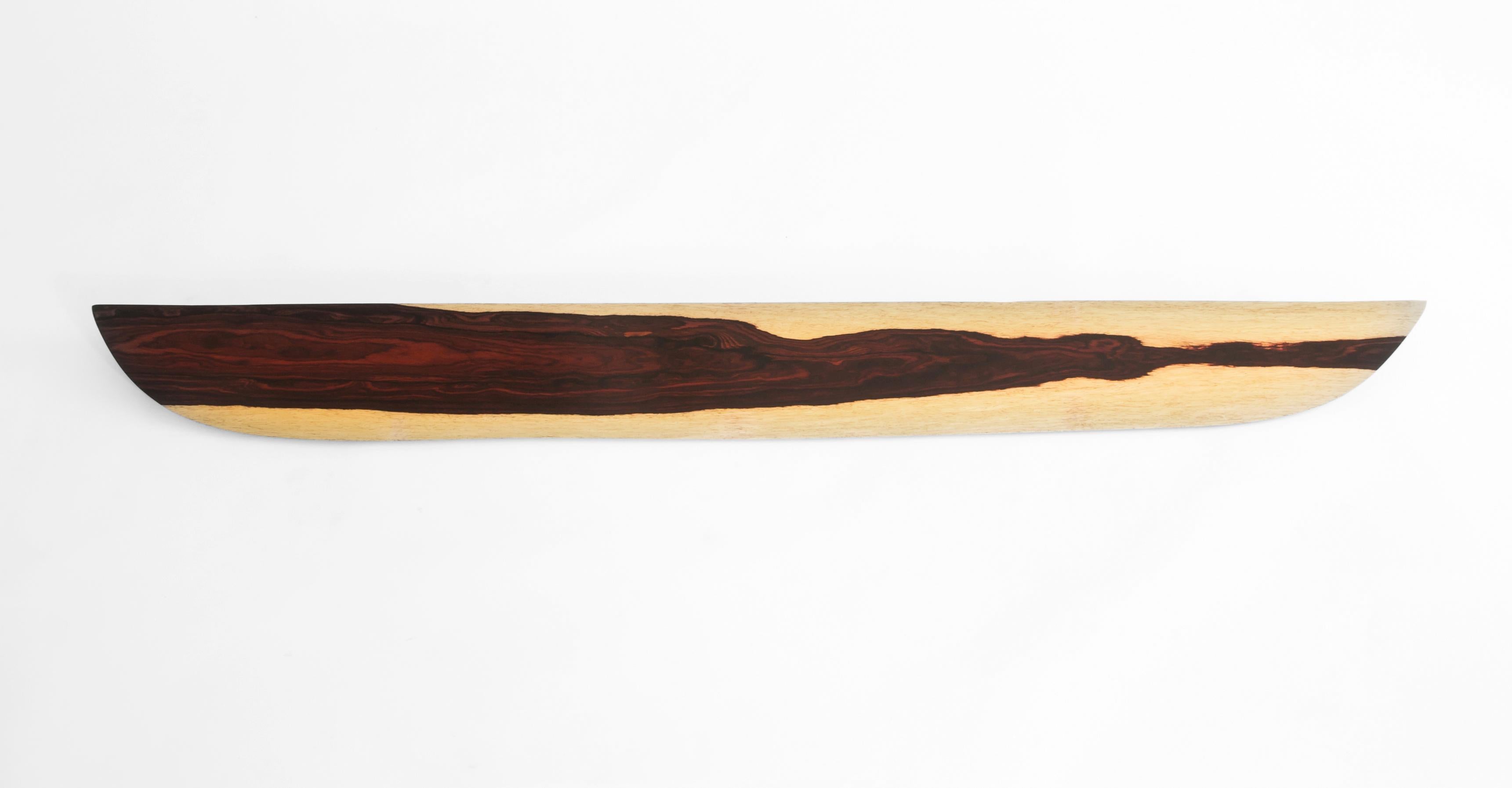 W1121 Wandregal zum Aufhängen aus Cocobolo-Holz von Jörg Pietschmann
Abmessungen: T 17,5 x B 162,5 x H 2 cm.
MATERIALIEN: Cocobolo-Holz.

In Pietschmanns Skulpturen erzählen Bäume, die jahrhundertelang Teil einer Landschaft waren und in Urkräften