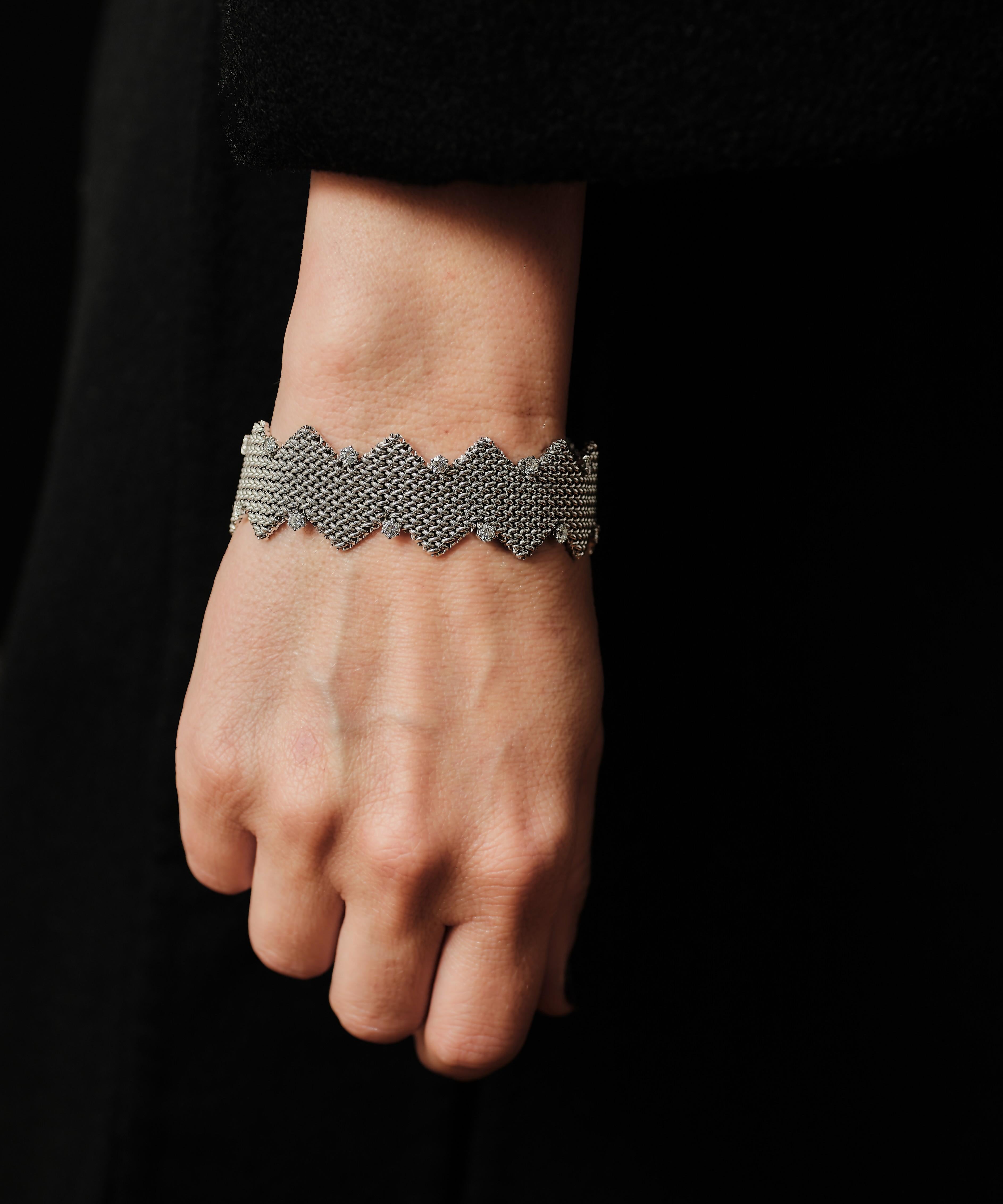 Braided links in 18 karat white gold forming a Chevron pattern, an inverted V pattern, with each side meeting at the point without interruption. The results are a seamless zig-zag pattern with each ‘valley’ marked with a brilliant cut diamond. 

In