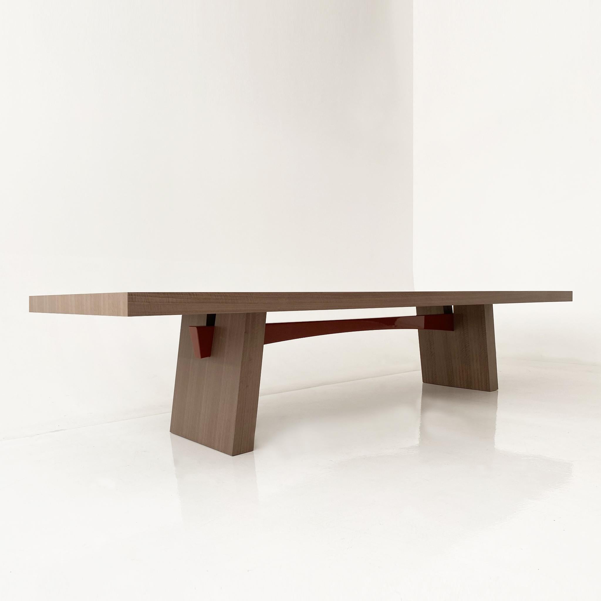 A dining table of generous proportions with a distinctly thick top and angled legs, its sleek design enhanced and enriched by the curve of its contrasting lacquered beam.
Designed in Elm wood with a dark-red gloss-lacquered beam, the WA table is